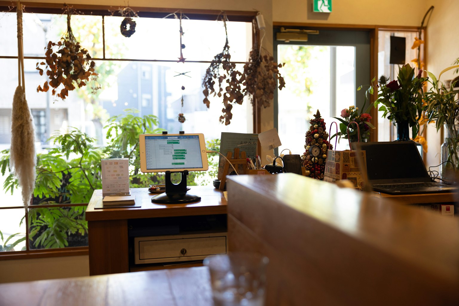 Interior of a cafe with a wooden counter and computer surrounded by plants