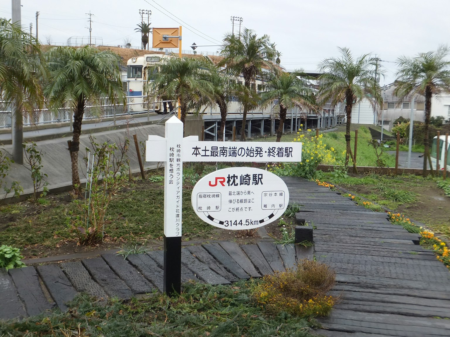 Panneau indicatif de la gare JR entouré de verdure