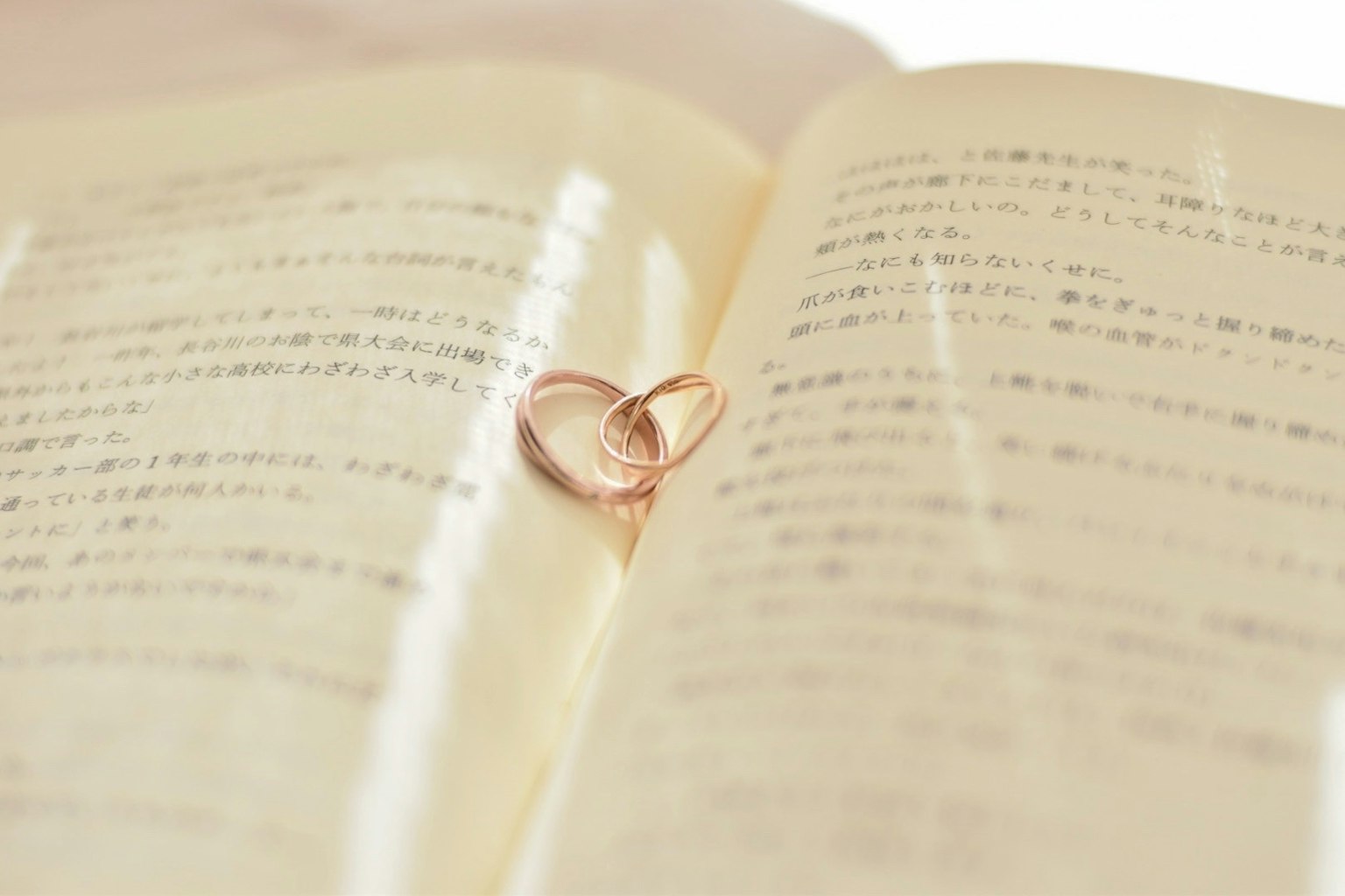 Heart-shaped wedding rings resting on open book pages