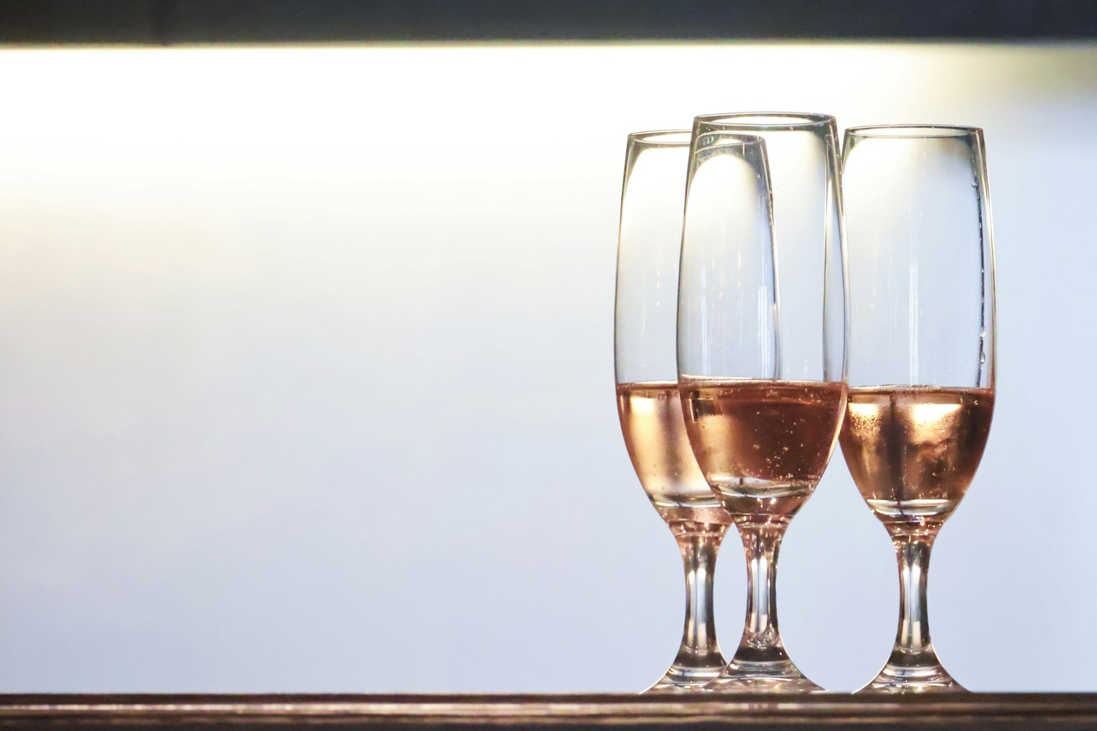 Tre flute di champagne piene di vino rosé su uno sfondo semplice