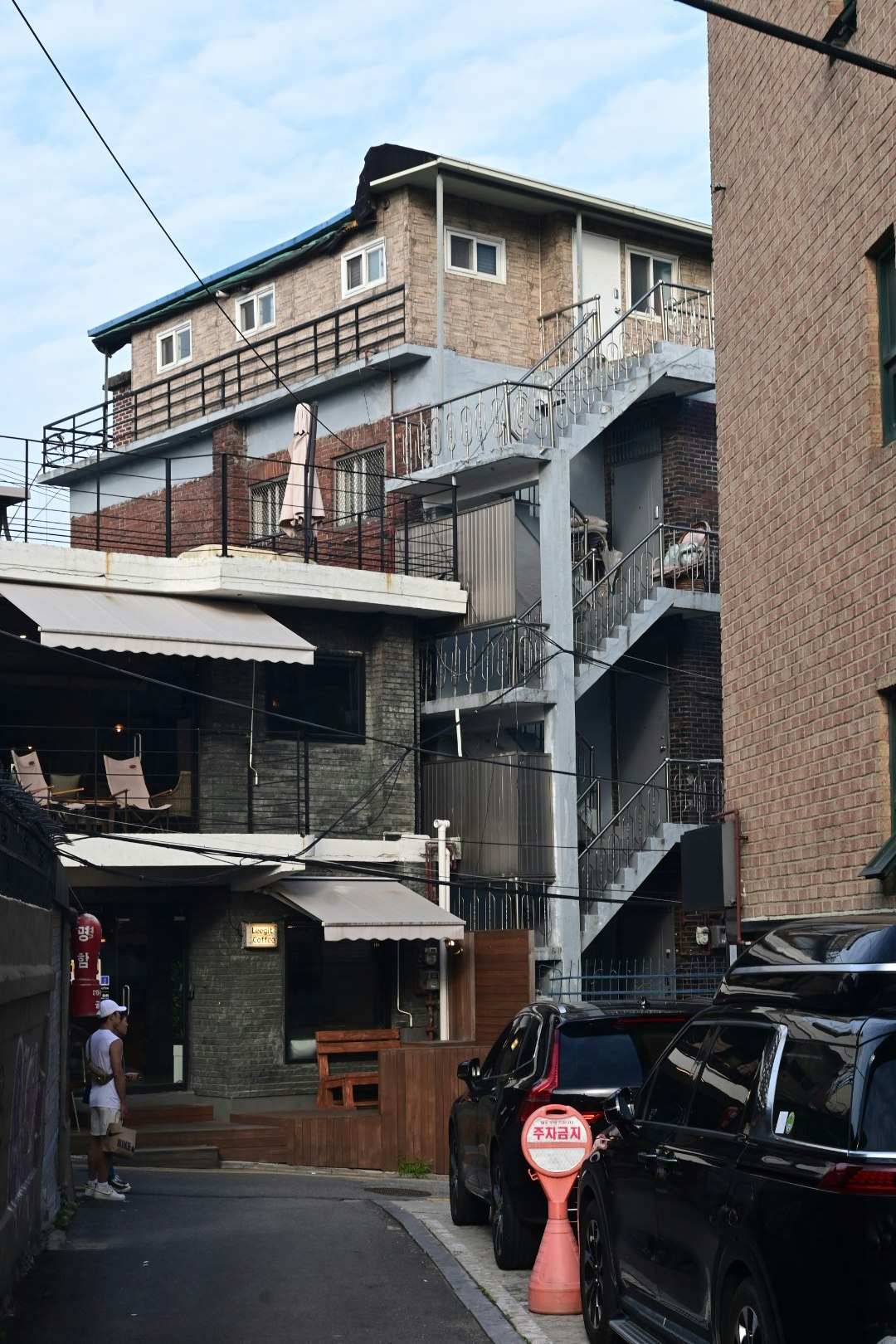 residential alley with staircases and parked cars in front of brick buildings