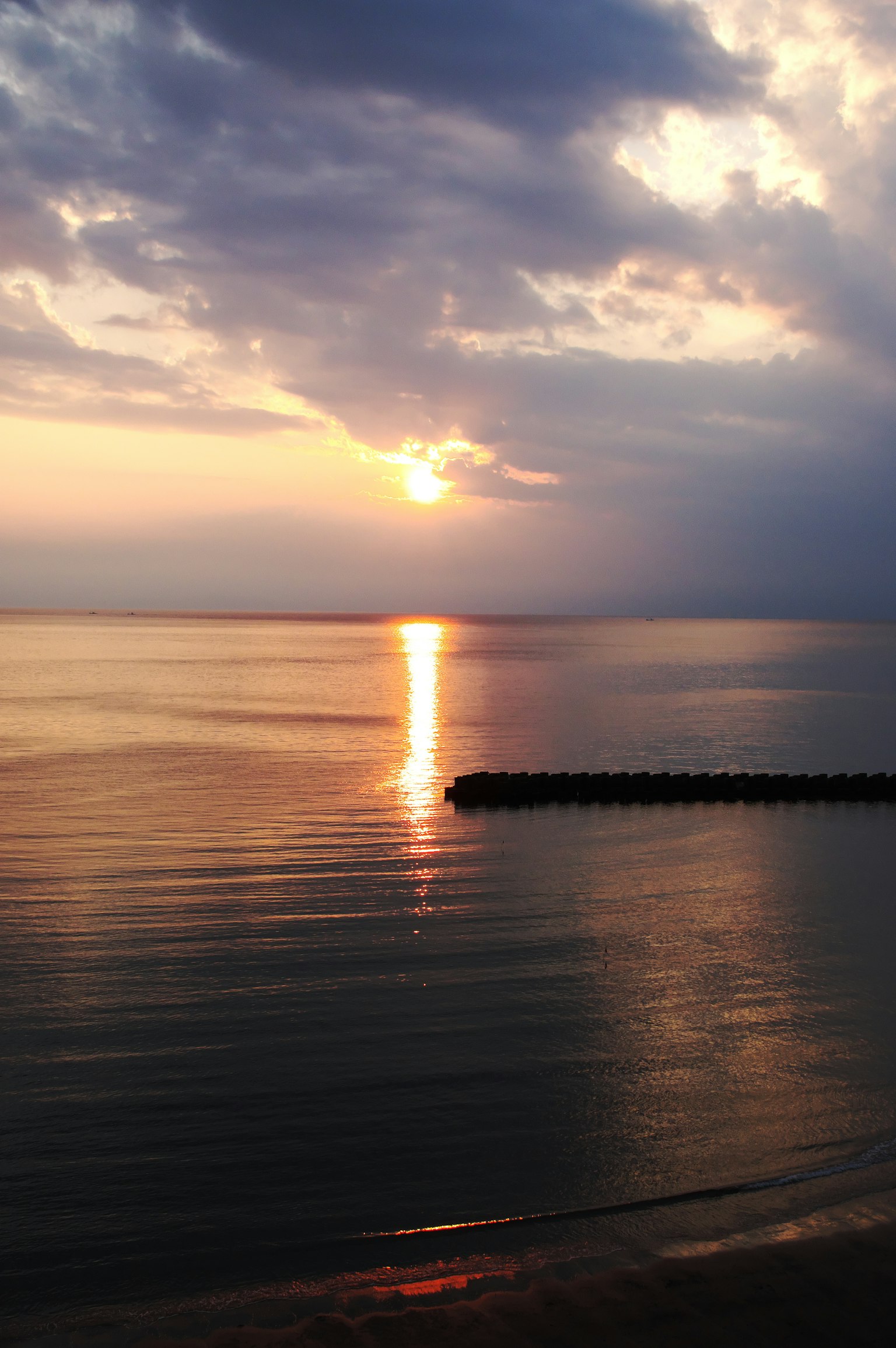 Serene sunset over calm waters with clouds