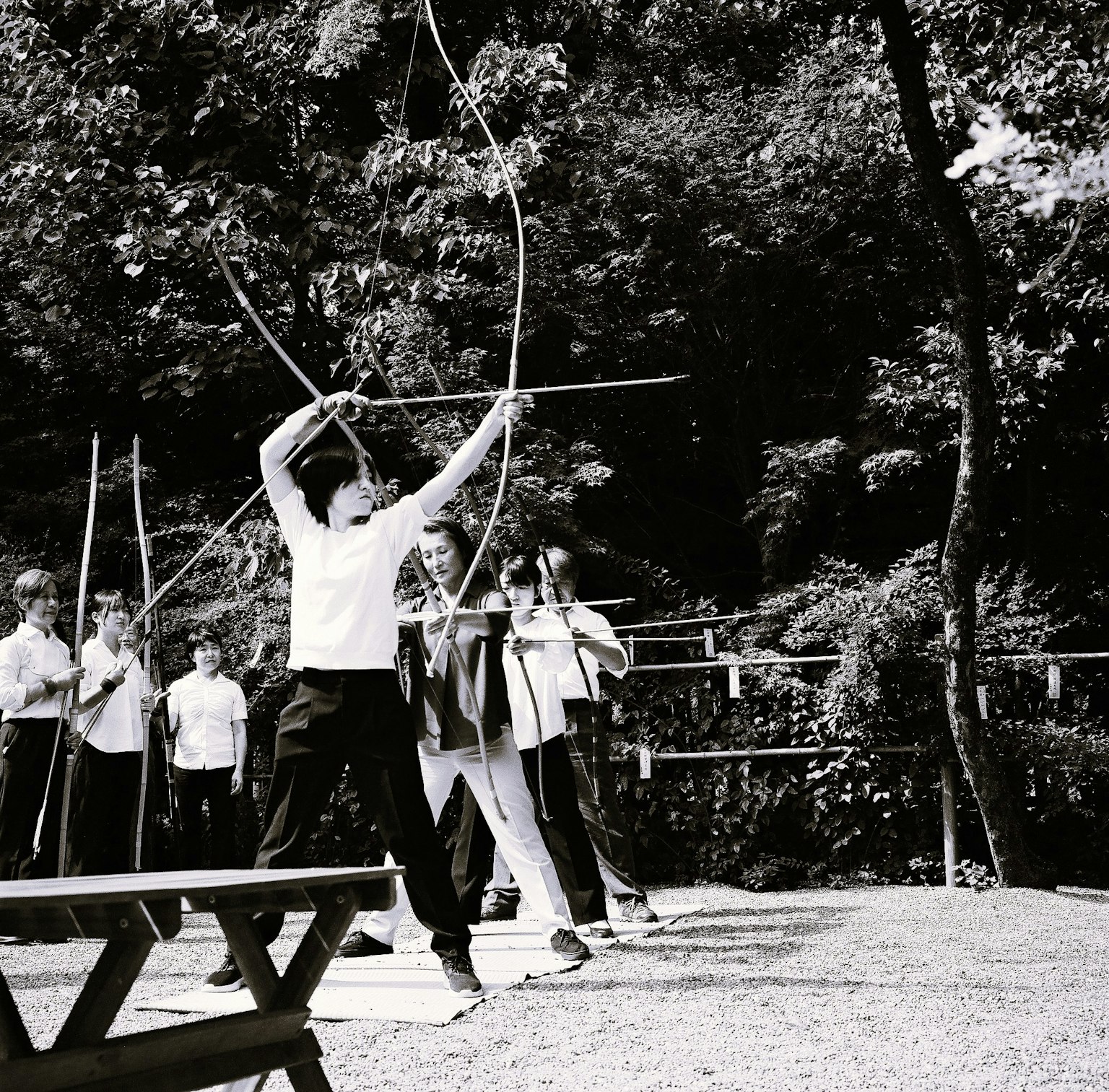 弓道の練習をする人々の白黒写真 森の中で弓を引く姿