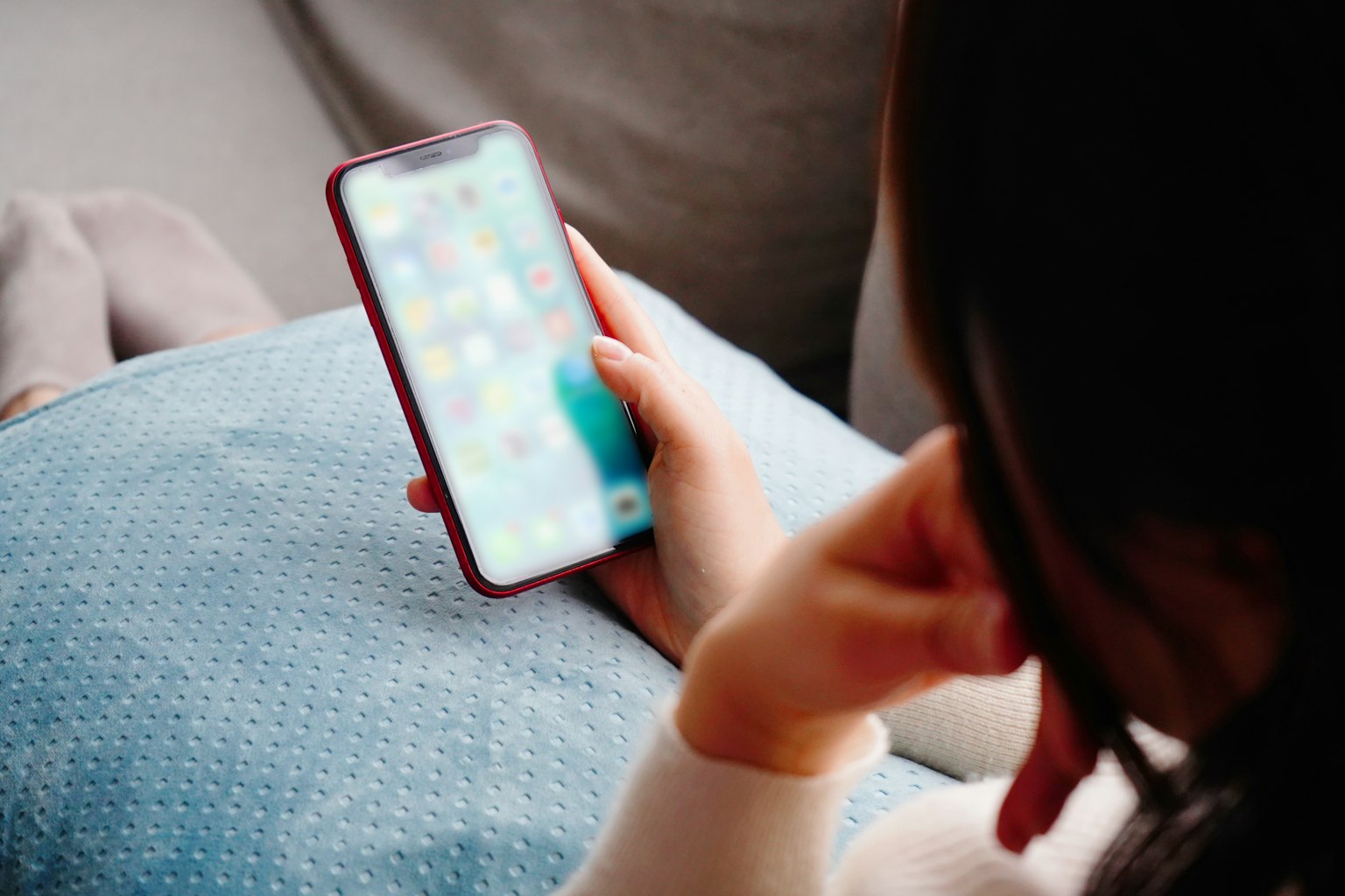 Primo piano della mano di una donna che usa uno smartphone su un cuscino blu