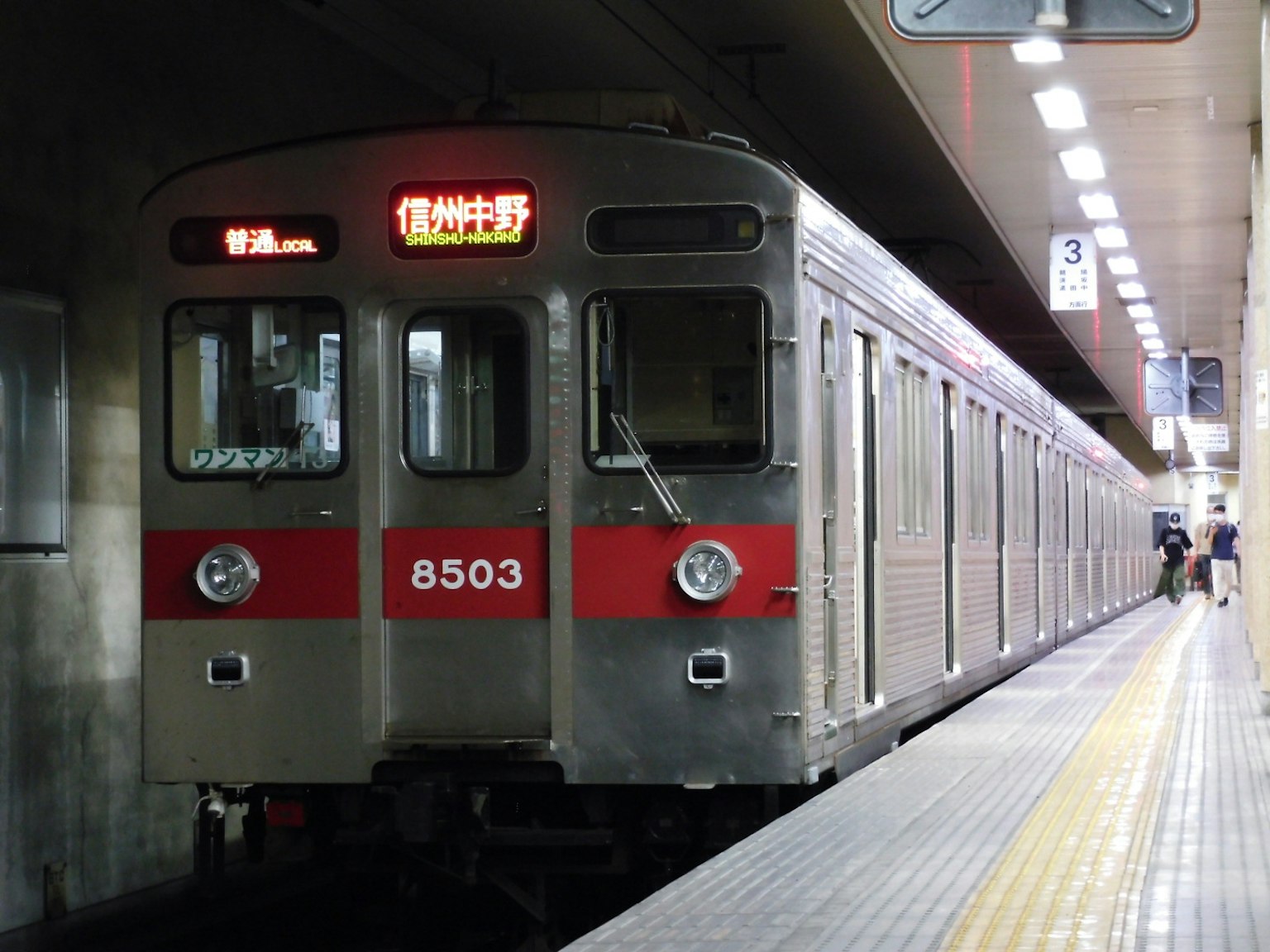 Train argenté avec des bandes rouges arrêté à la gare