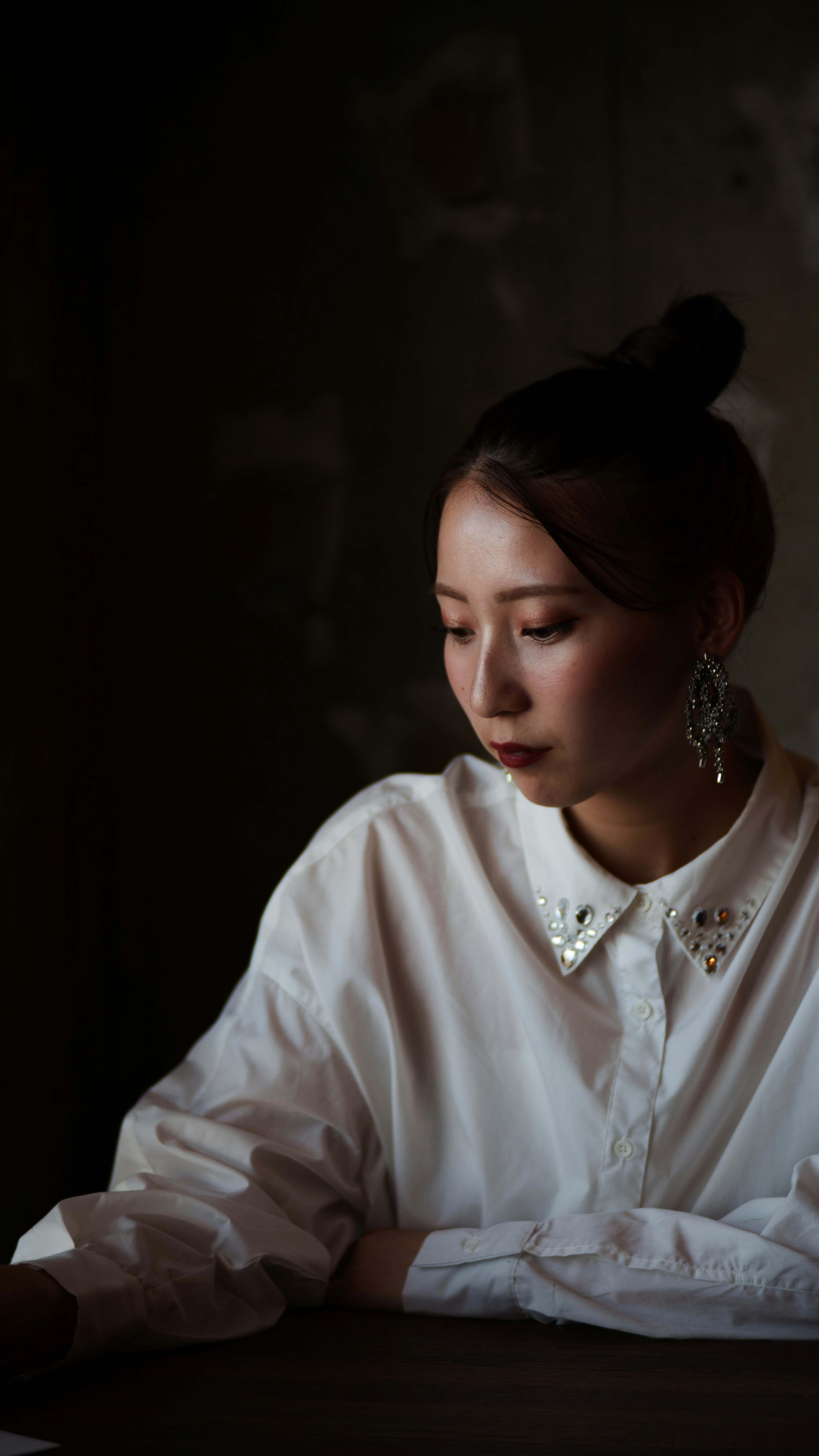 光影交錯中低頭看手的女性側臉