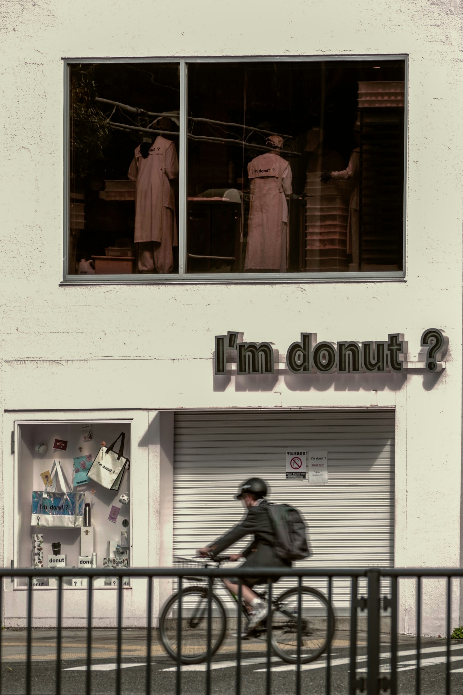 Stylish donut shop exterior featuring a cyclist and two mannequins visible in the window