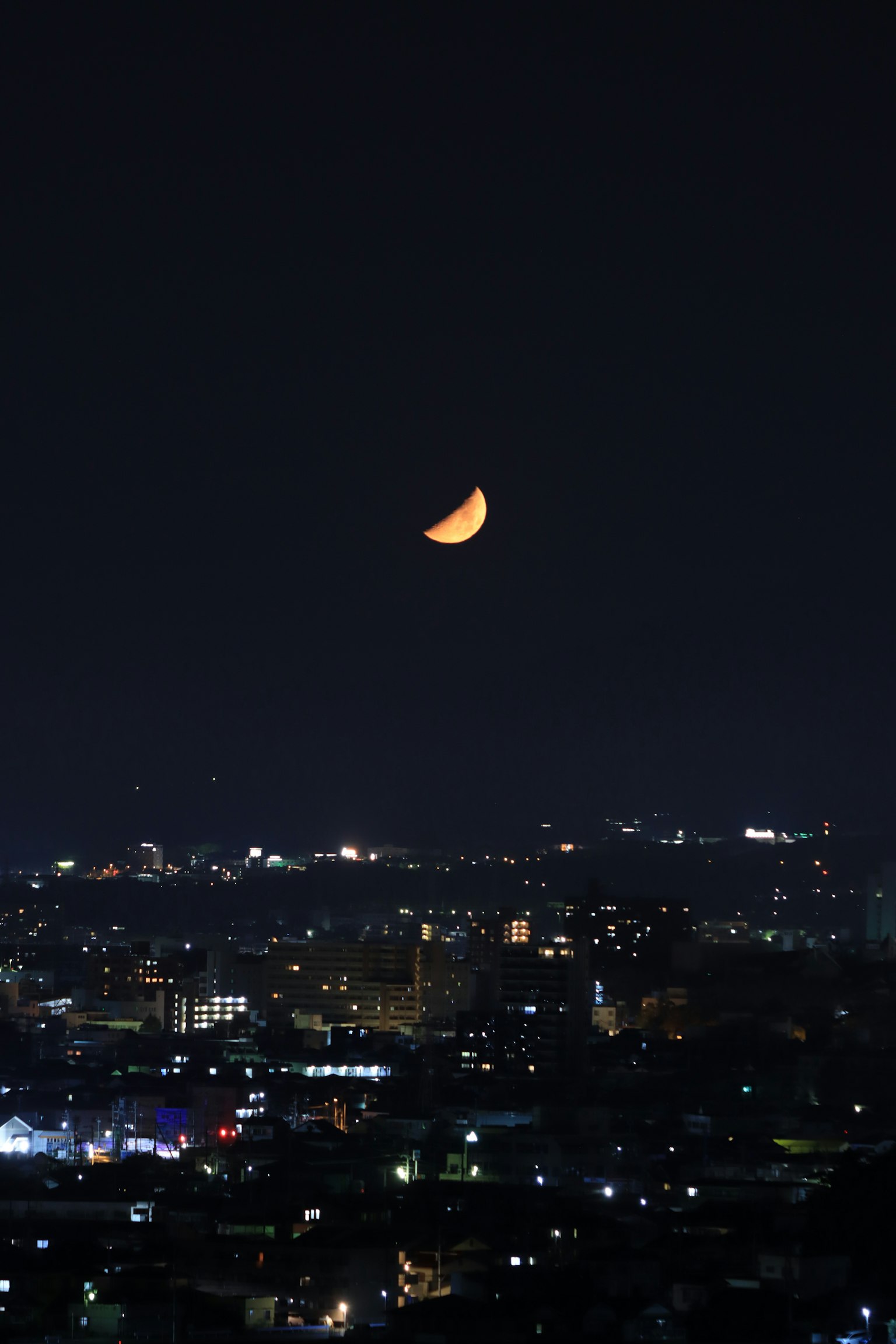Nachthimmel mit einem zunehmenden Mond über der Stadtsilhouette