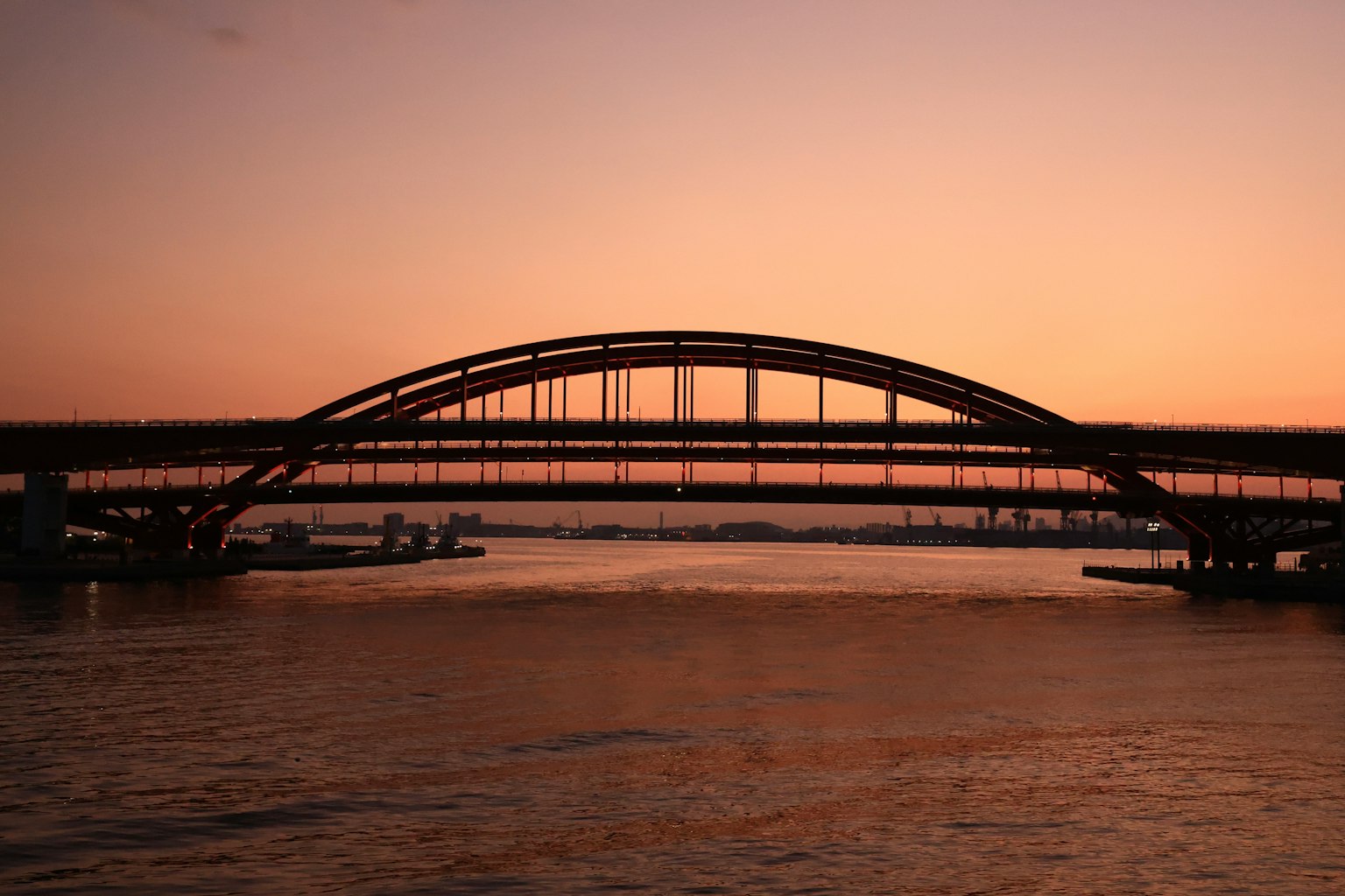 Silhouette einer schönen Brücke in der Dämmerung Sanfte orange und lila Töne, die sich im Wasser spiegeln