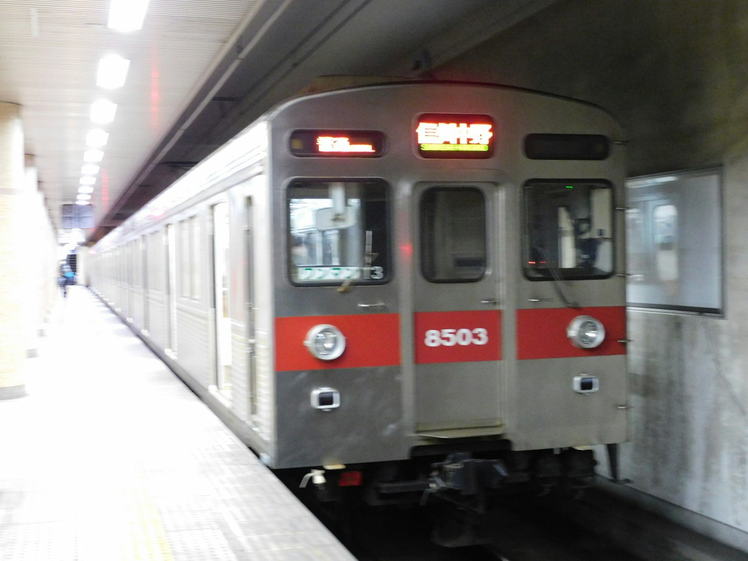 赤いストライプのある銀色の地下鉄車両が駅に停車している