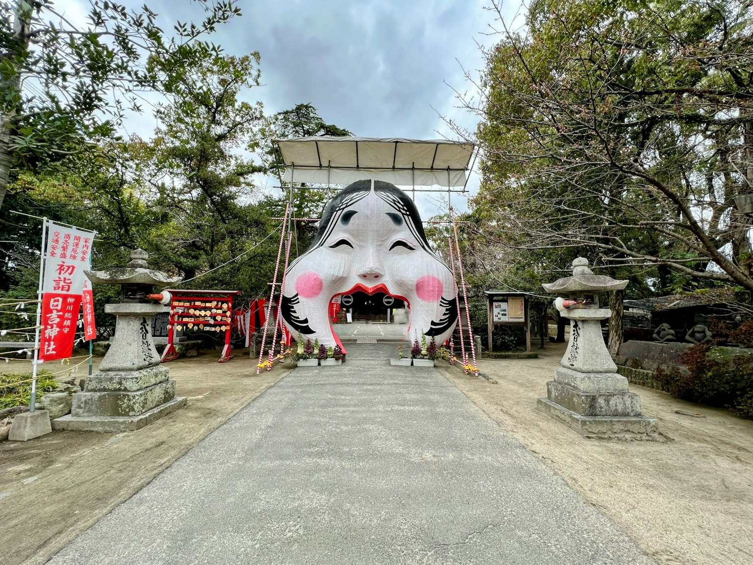 Large decorative face structure at the entrance of a shrine featuring distinctive red cheeks