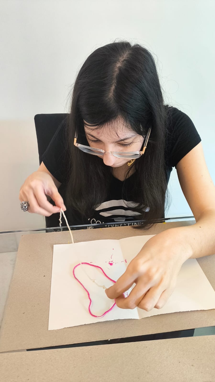 机の上で糸を使って絵を描く女性