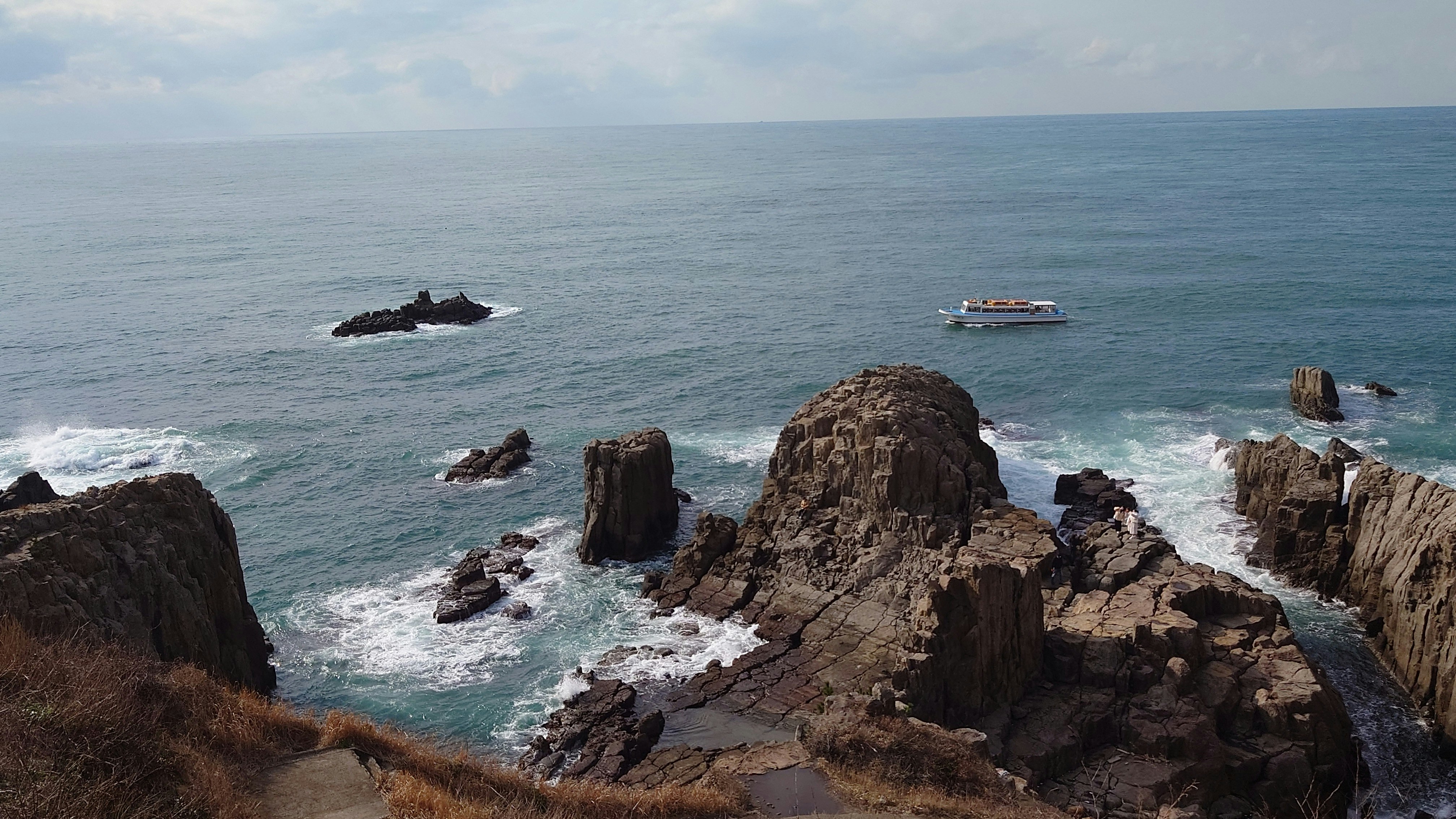 東尋坊の岩場と日本海、遊覧船が見える海景の画像