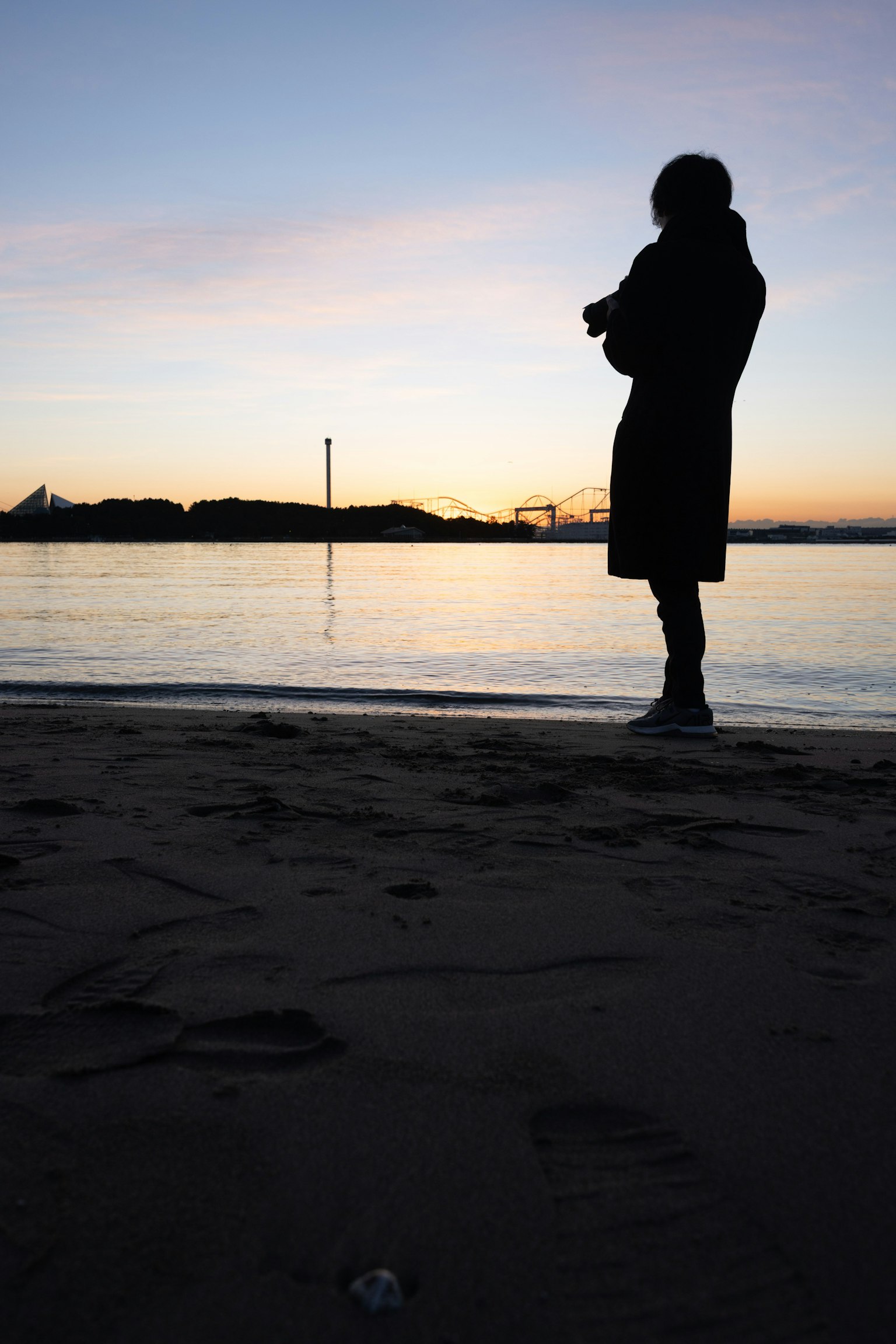 Silhouette di una persona in piedi sulla spiaggia al tramonto