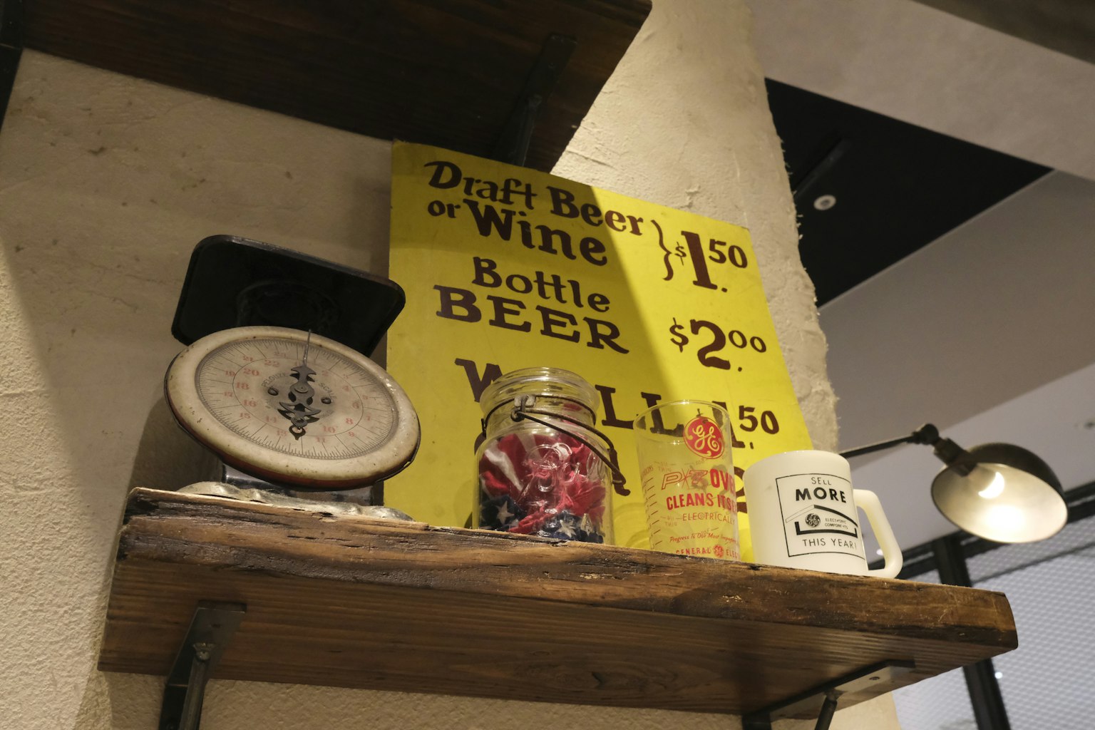 Cartel vintage y recipientes de bebidas exhibidos en una estantería de madera