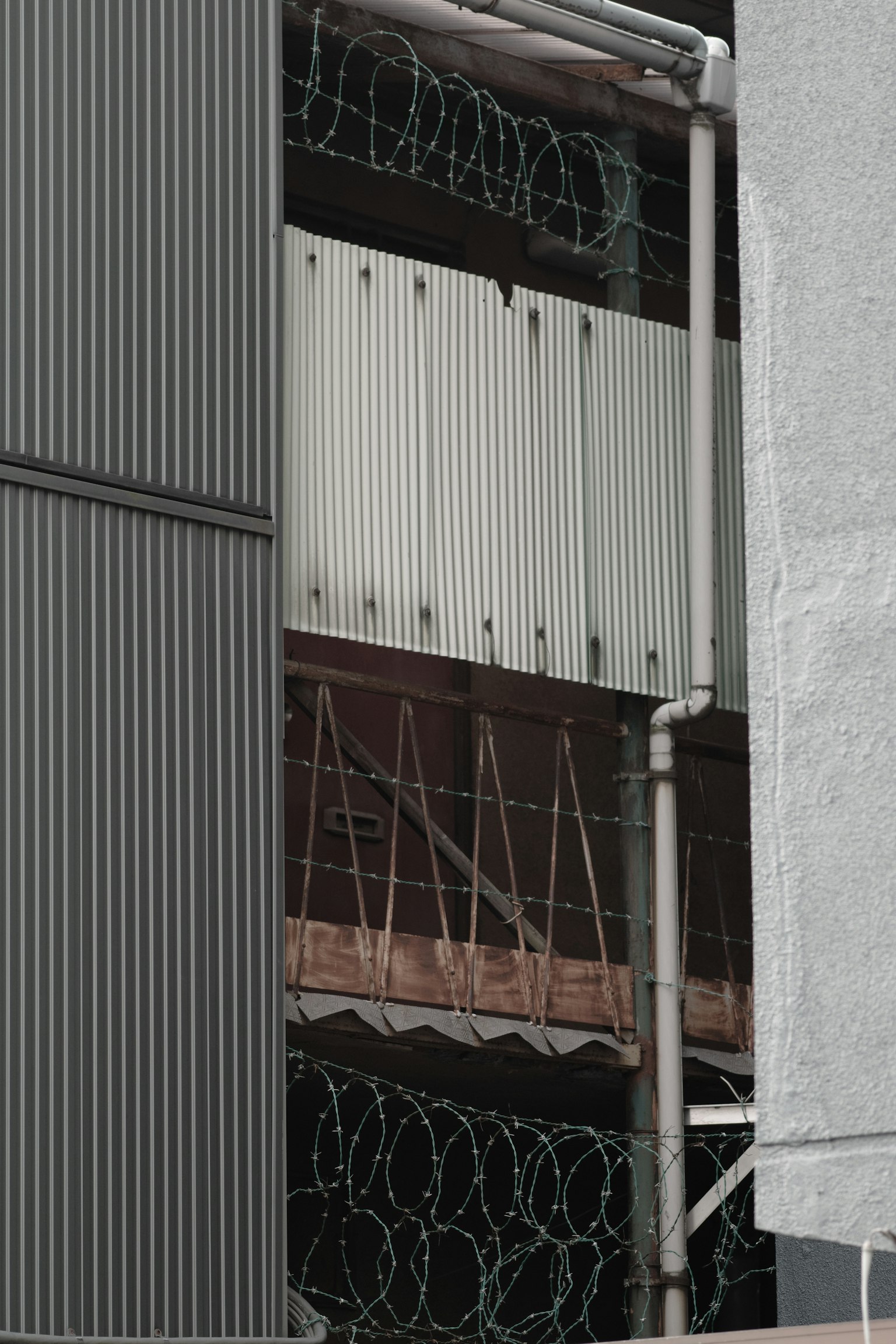 Structure with white panels surrounded by metal walls and barbed wire