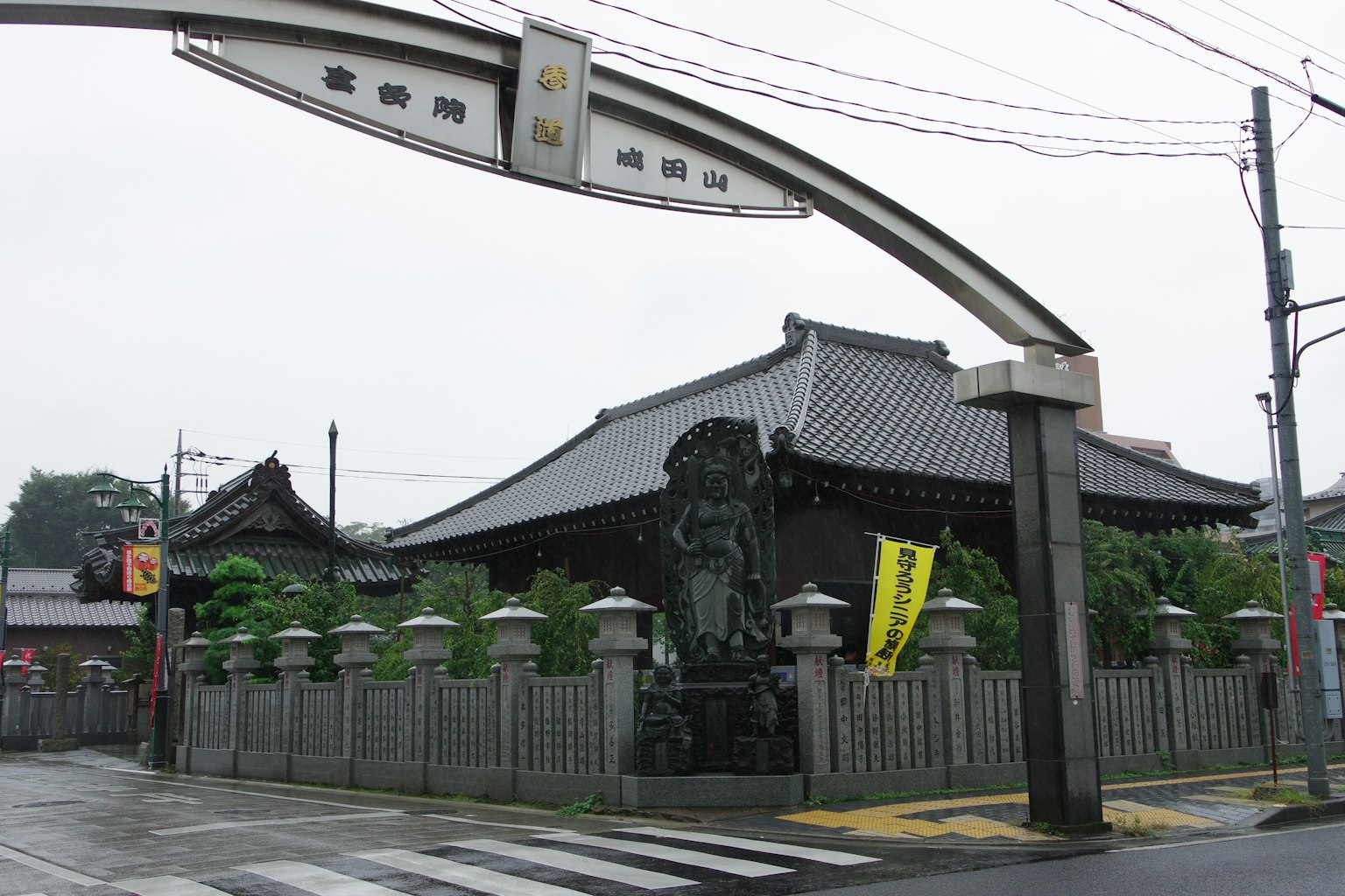 传统寺庙的拱形入口，背景是独特的屋顶和周围的绿意