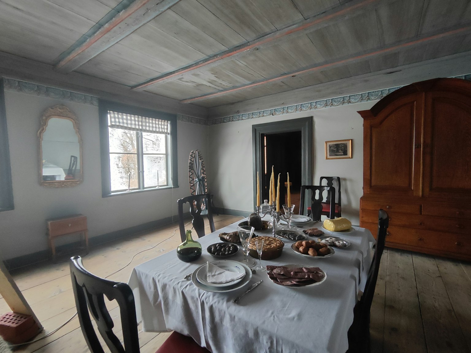 Innenansicht eines traditionellen Esszimmers mit einem Tisch, der mit einem weißen Tischdecken und Geschirr gedeckt ist, Ambiente Möbel und Fenster