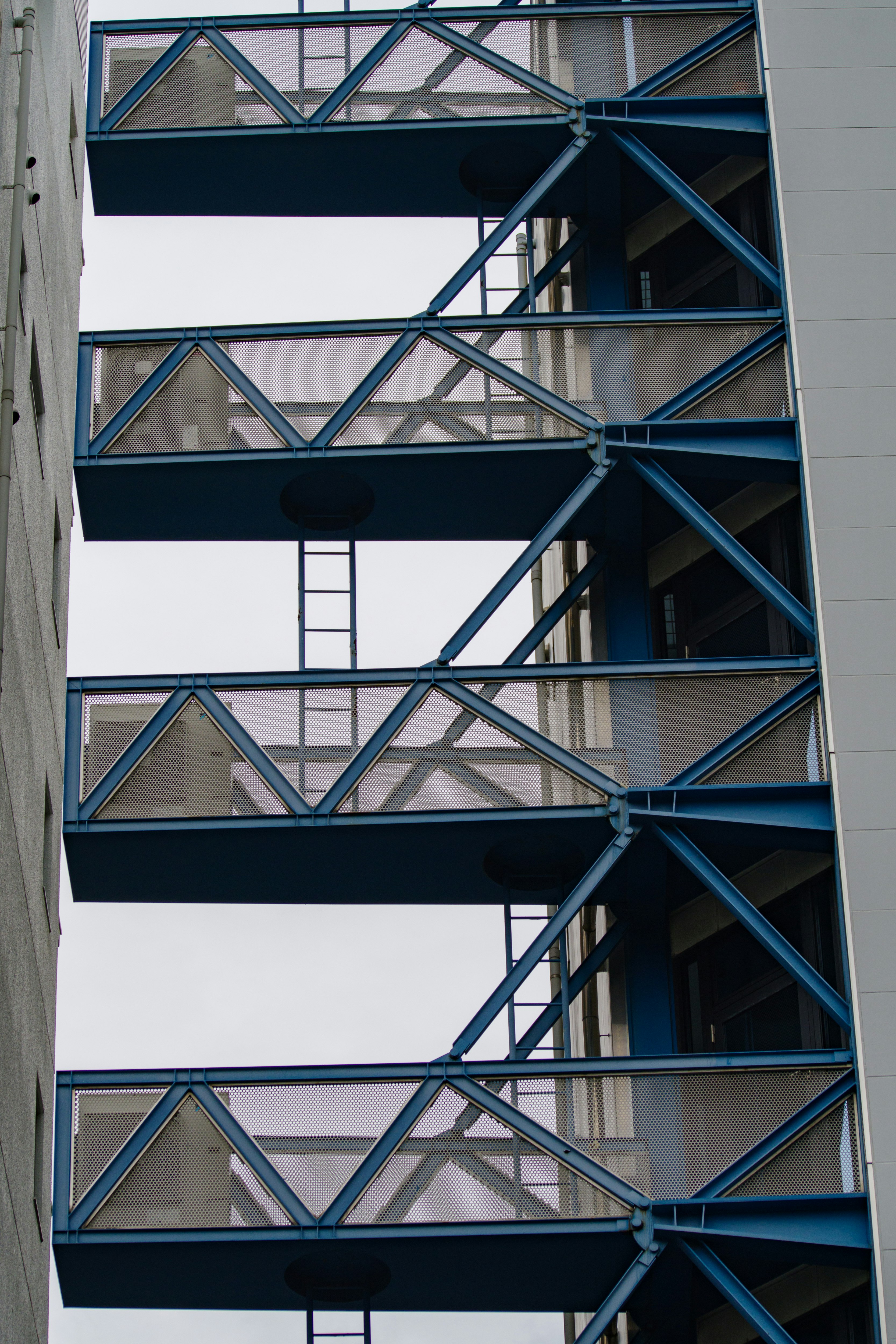 Façade d’un bâtiment moderne avec des escaliers de secours en acier bleu