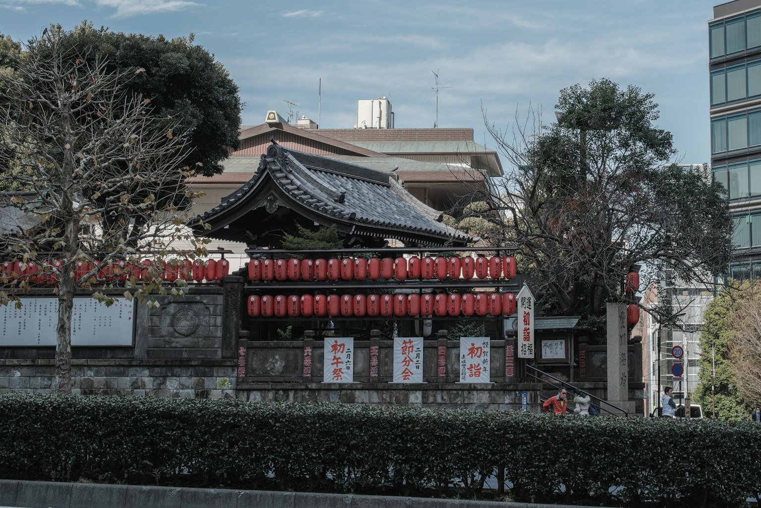 Traditional Japanese building adorned with red lanterns alongside modern buildings