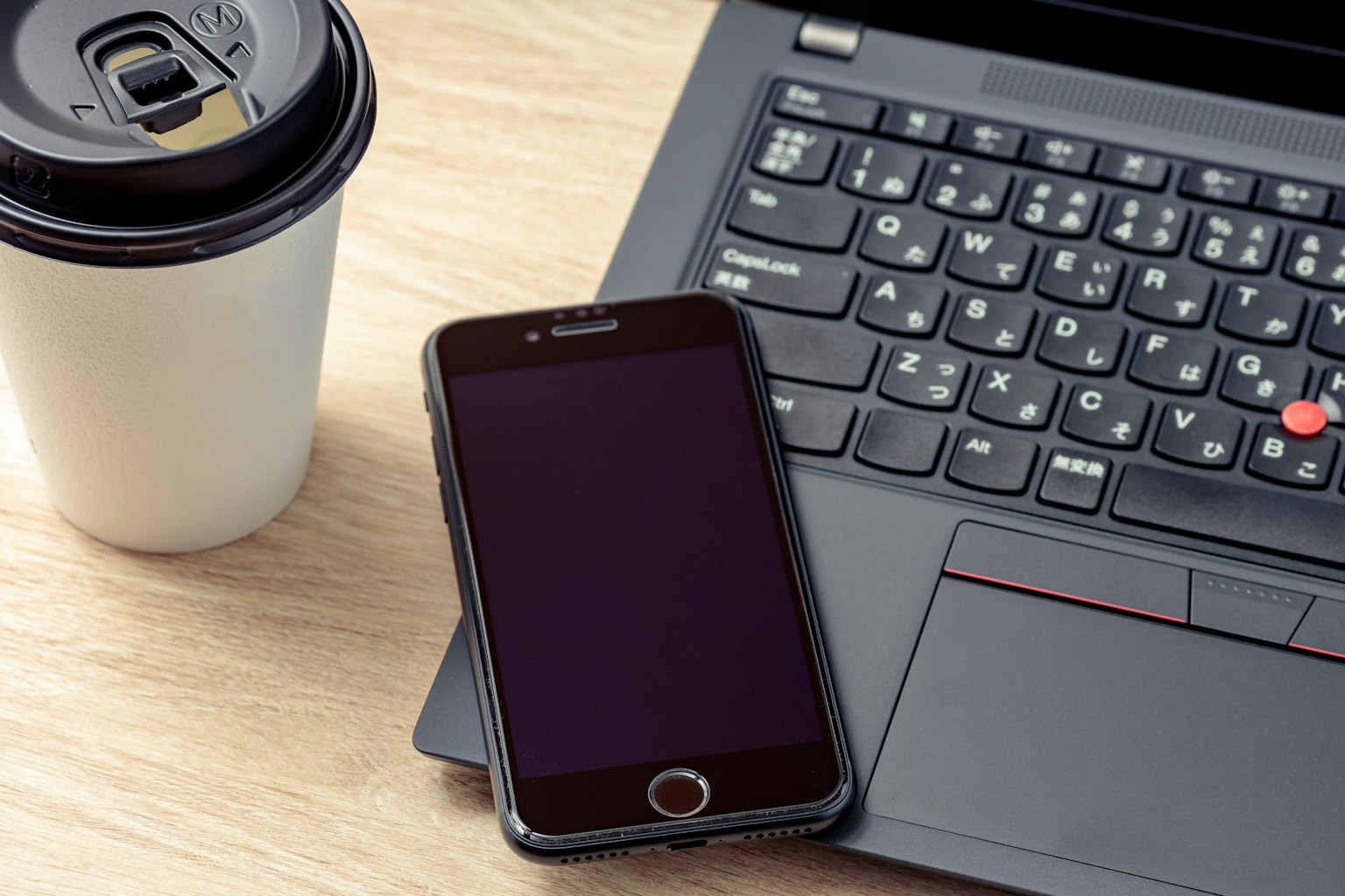 Smartphone à côté d'un ordinateur portable et d'une tasse de café sur une table en bois