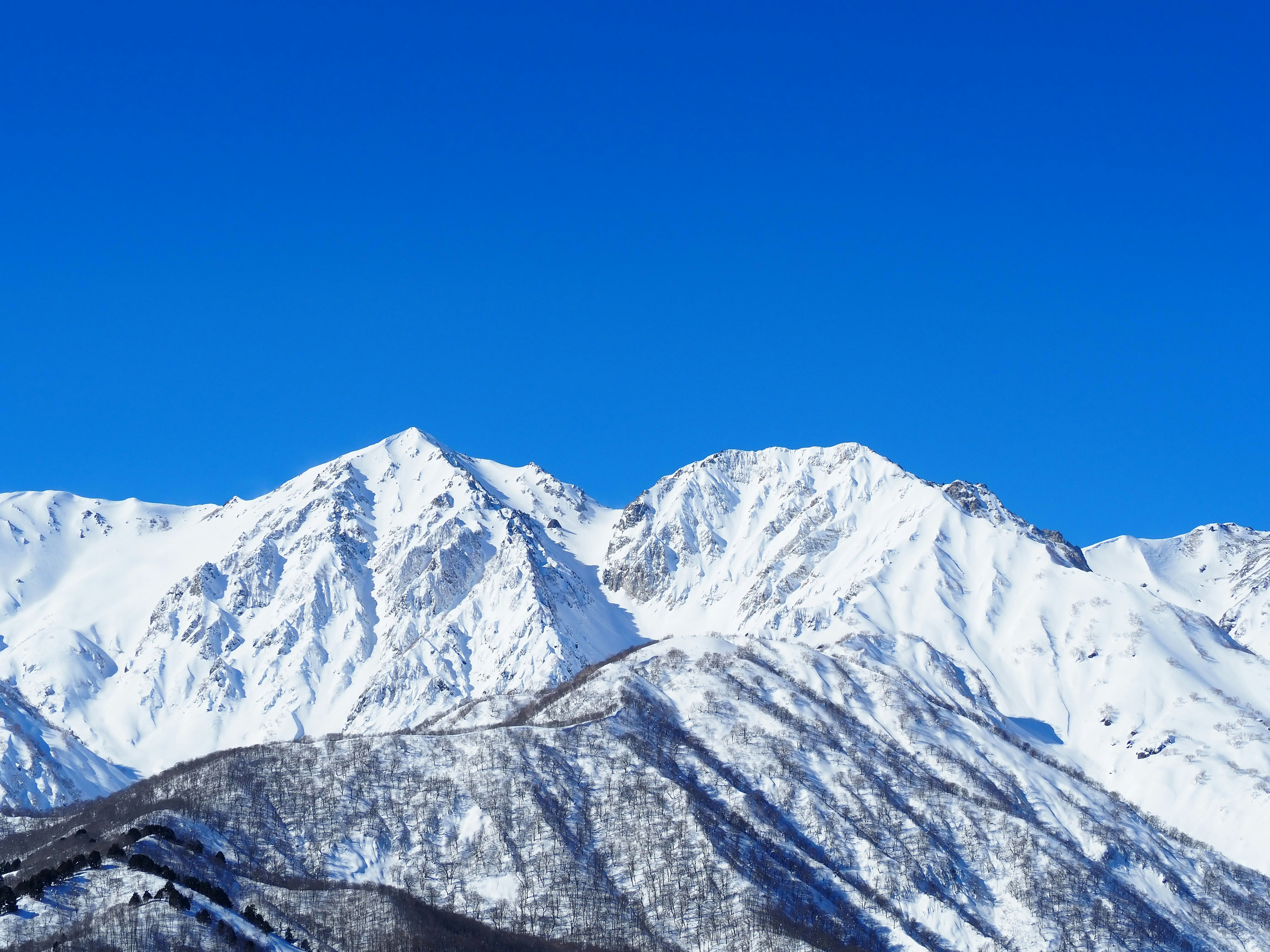 青空の下にそびえる雪山の稜線