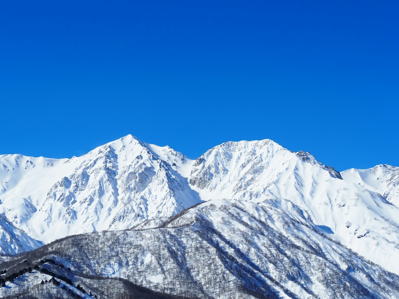 雪覆盖的山脉在晴朗的蓝天下