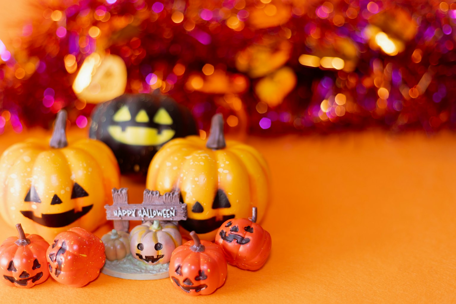 Decorazioni di Halloween con zucche arancioni e festoni viola su uno sfondo arancione