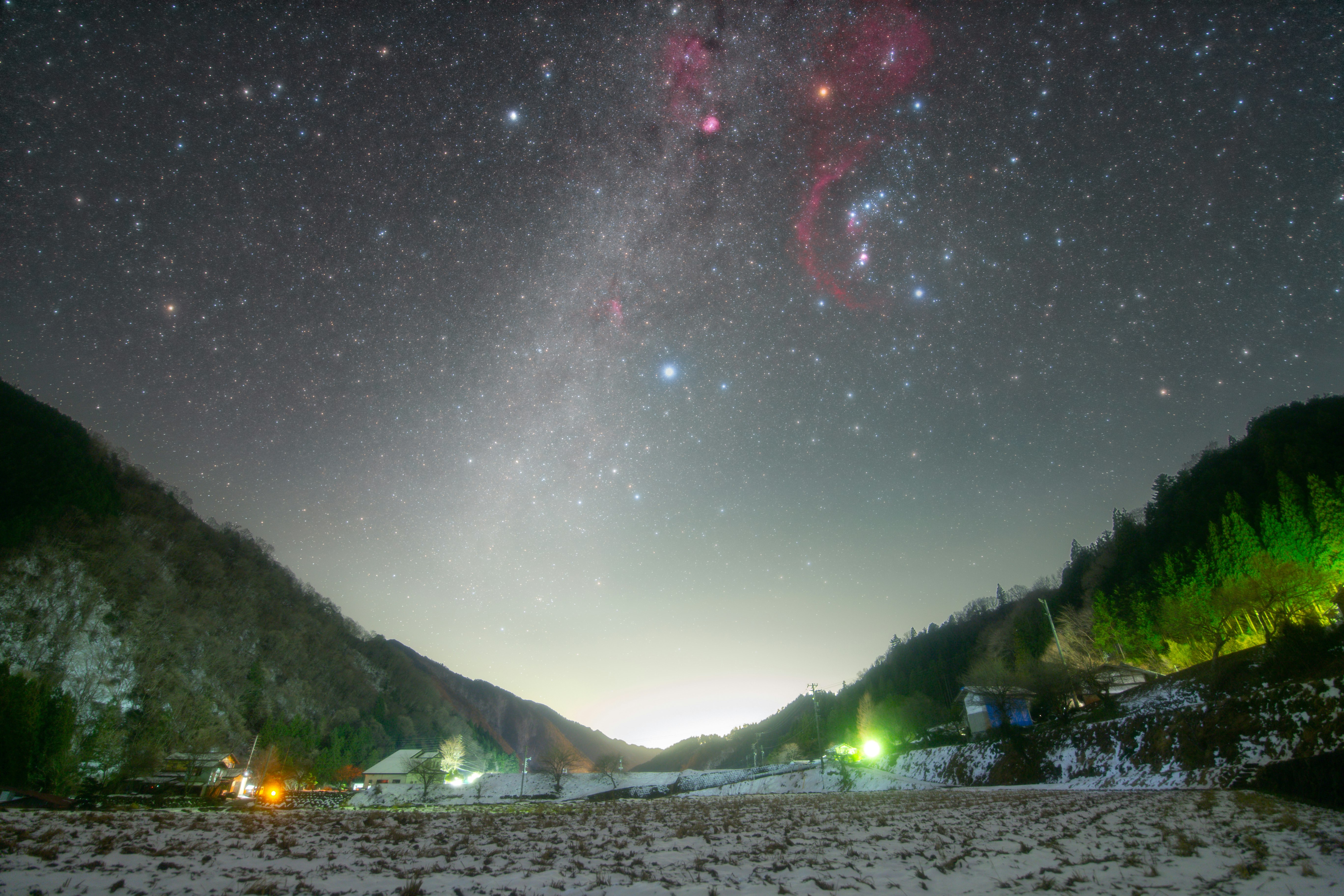 雪の河原と山並みを見下ろす夜空の星空
