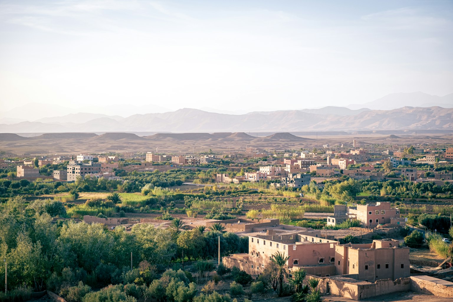 Amplio paisaje verde con un pueblo y montañas al fondo