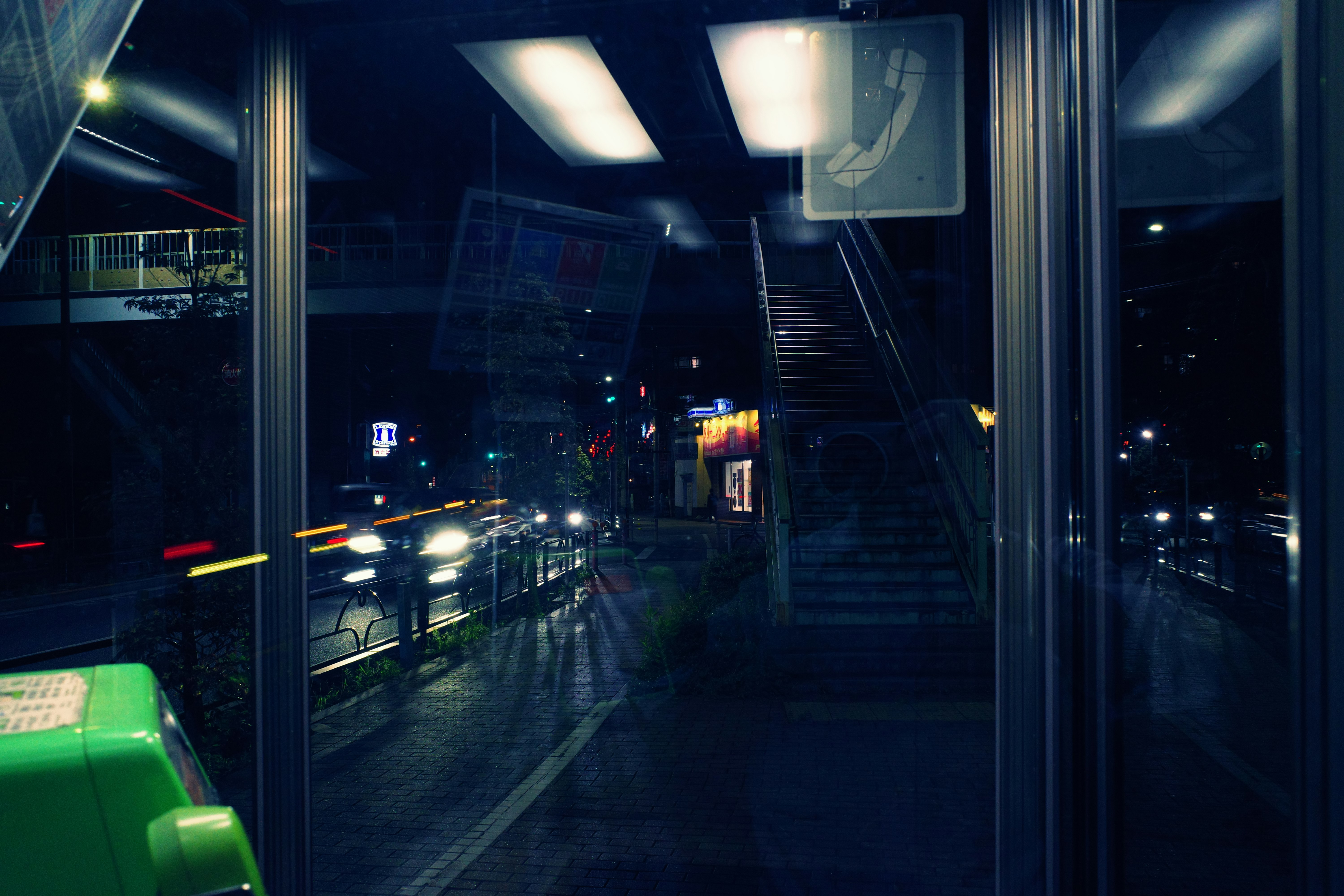 night view through a train window over elevated tracks and city neon