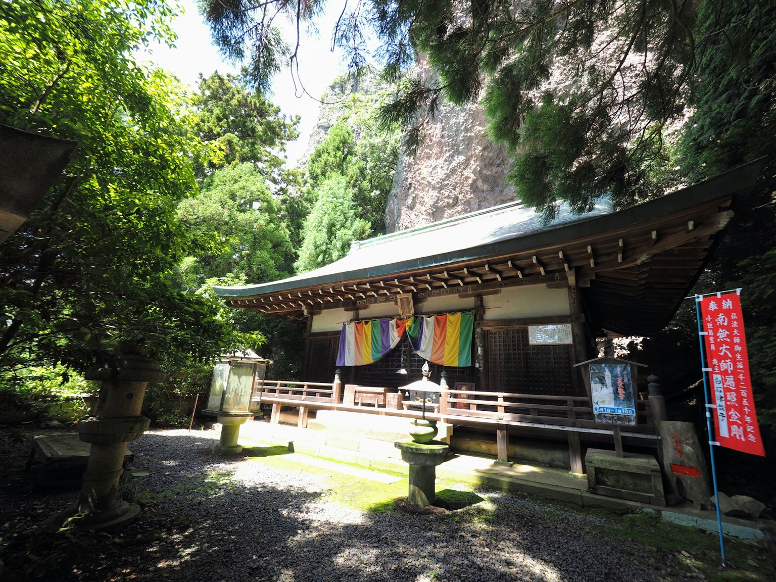 Tempio giapponese tradizionale circondato da vegetazione con tessuti colorati appesi
