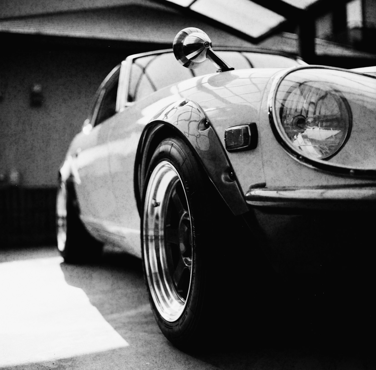 Black and white photo of a classic sports car emphasizing its side profile