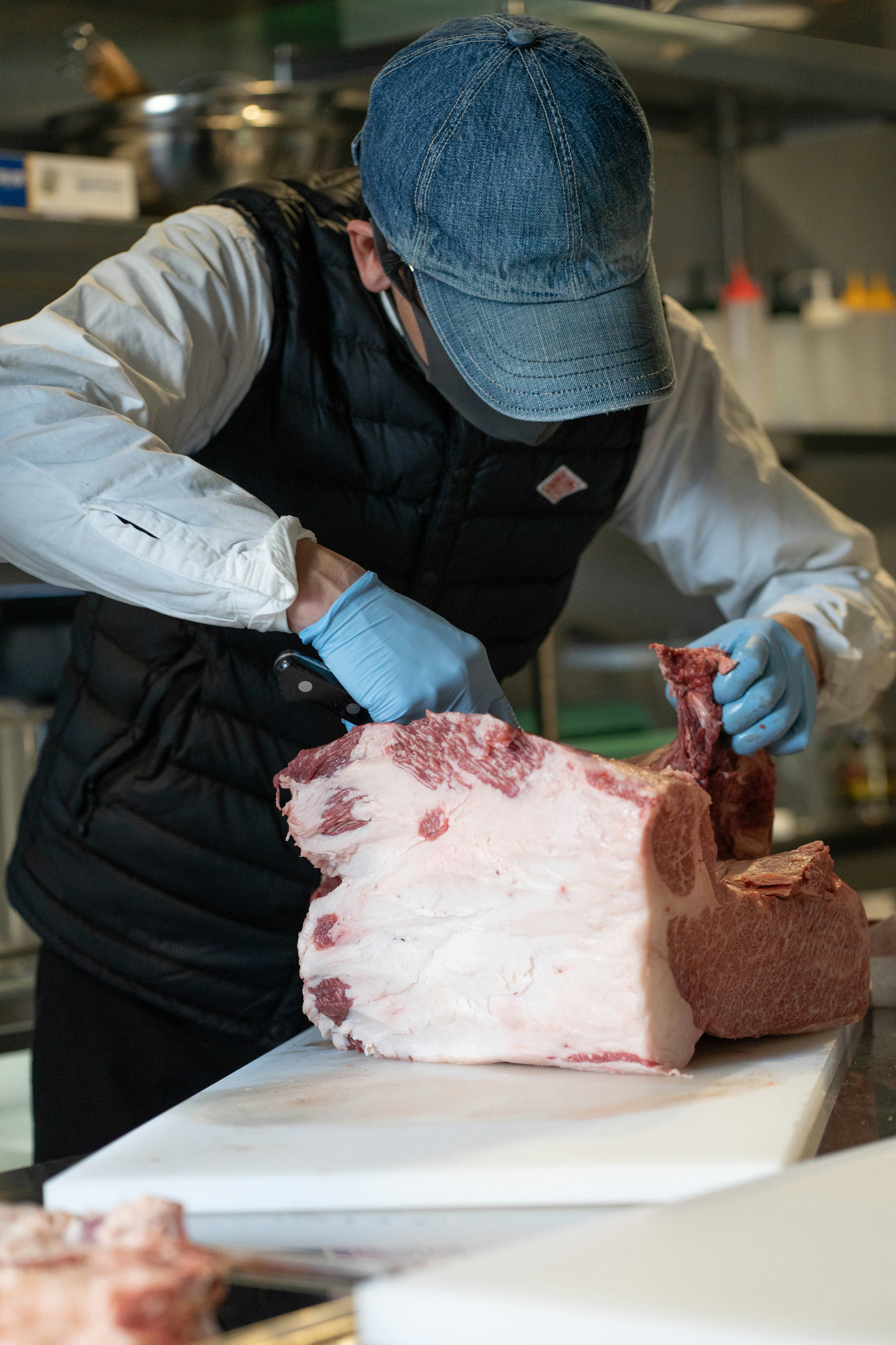 indoor kitchen scene of a butcher cutting meat