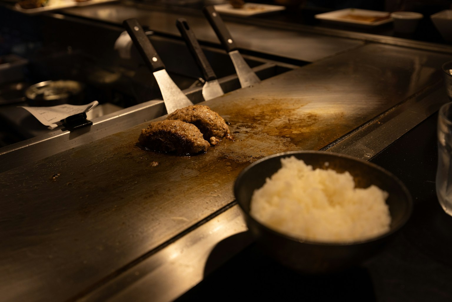 一個場景，鐵板上有烤漢堡餅和一碗白米飯