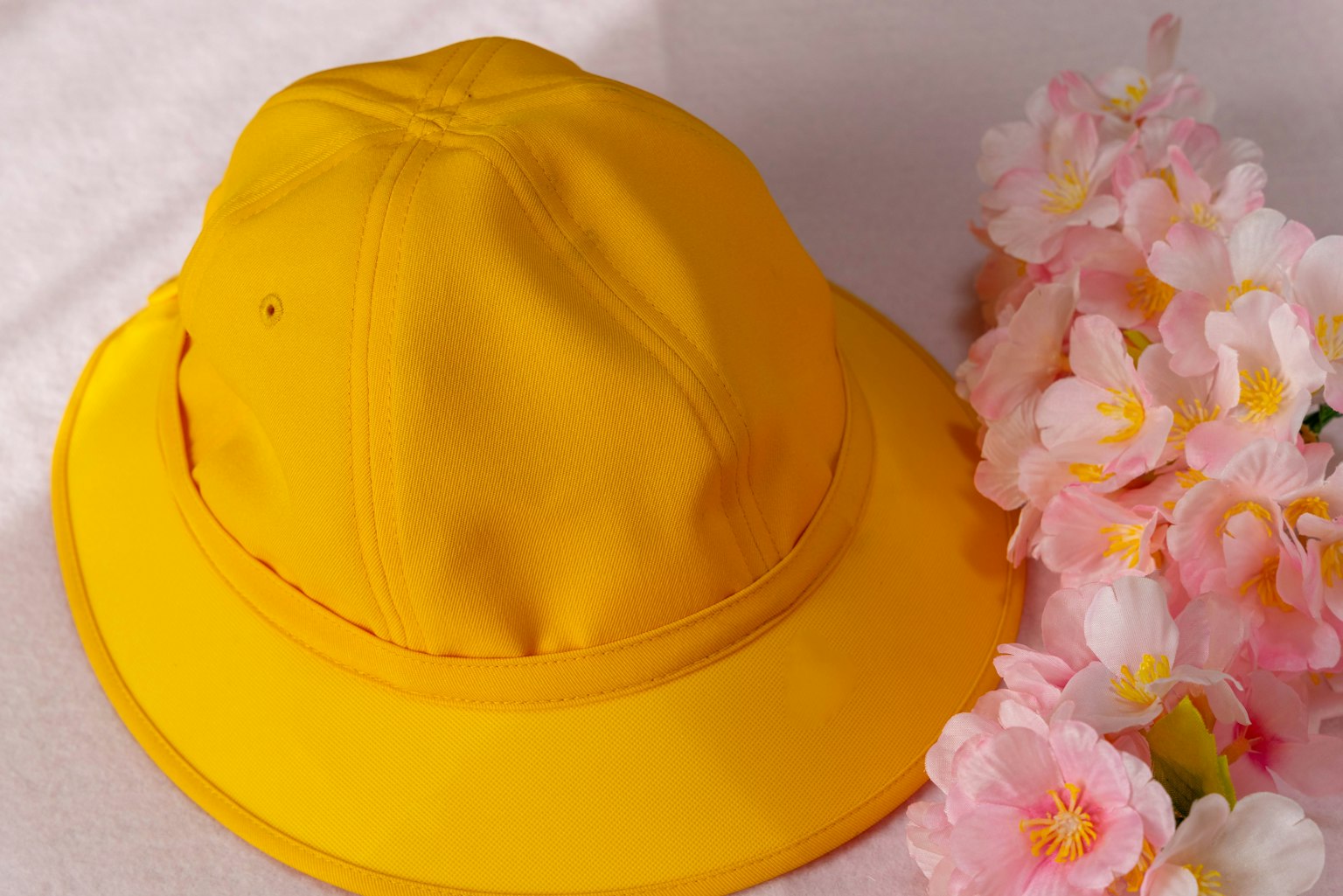 Topi kuning di samping hiasan bunga pink