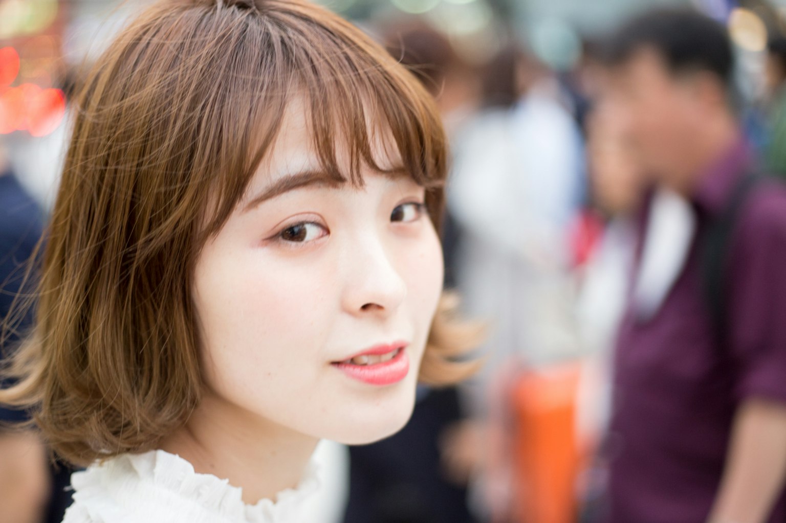 A young woman smiling at the camera with people in the background