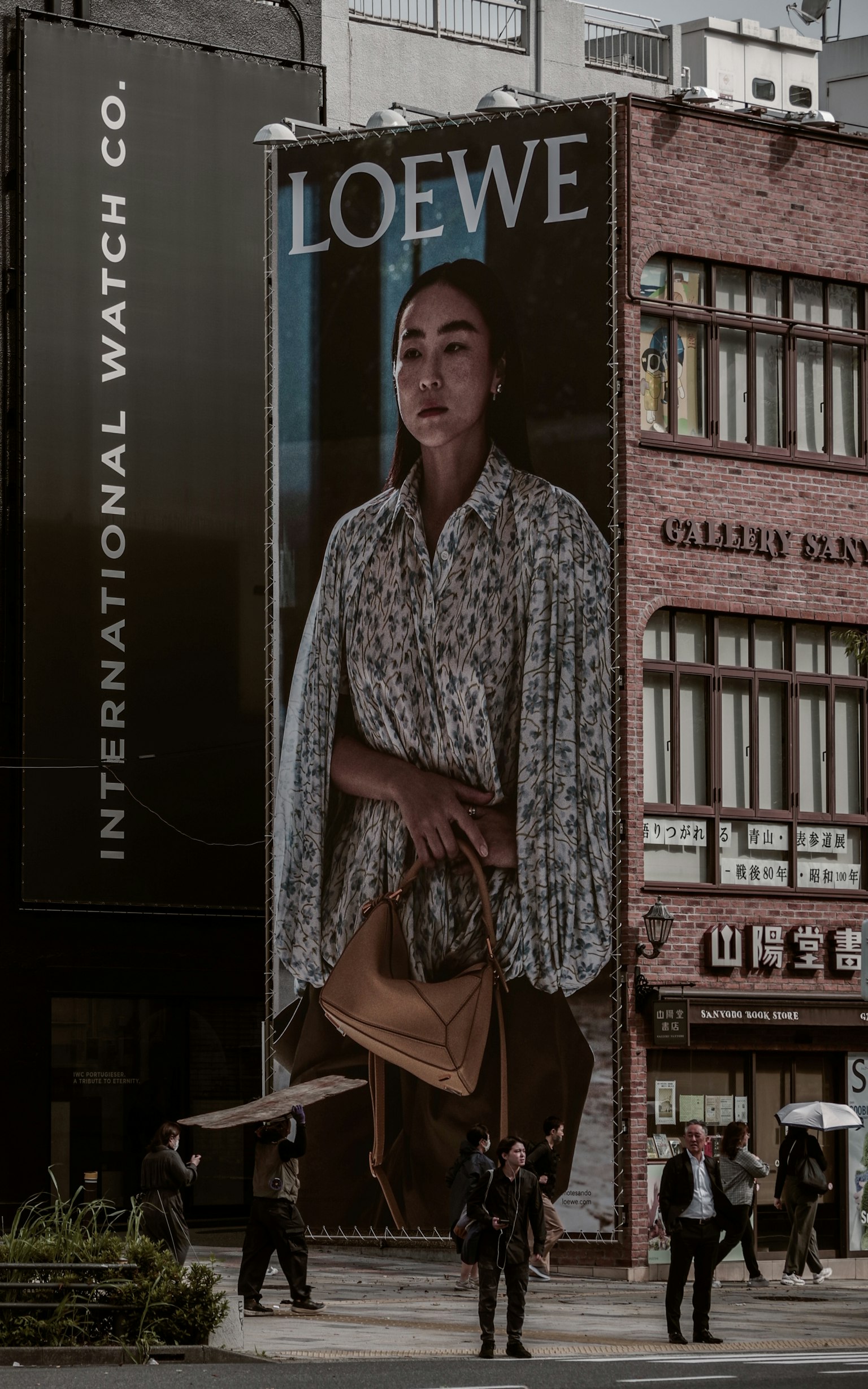 Una donna con una borsa davanti a una pubblicità LOEWE in un contesto urbano