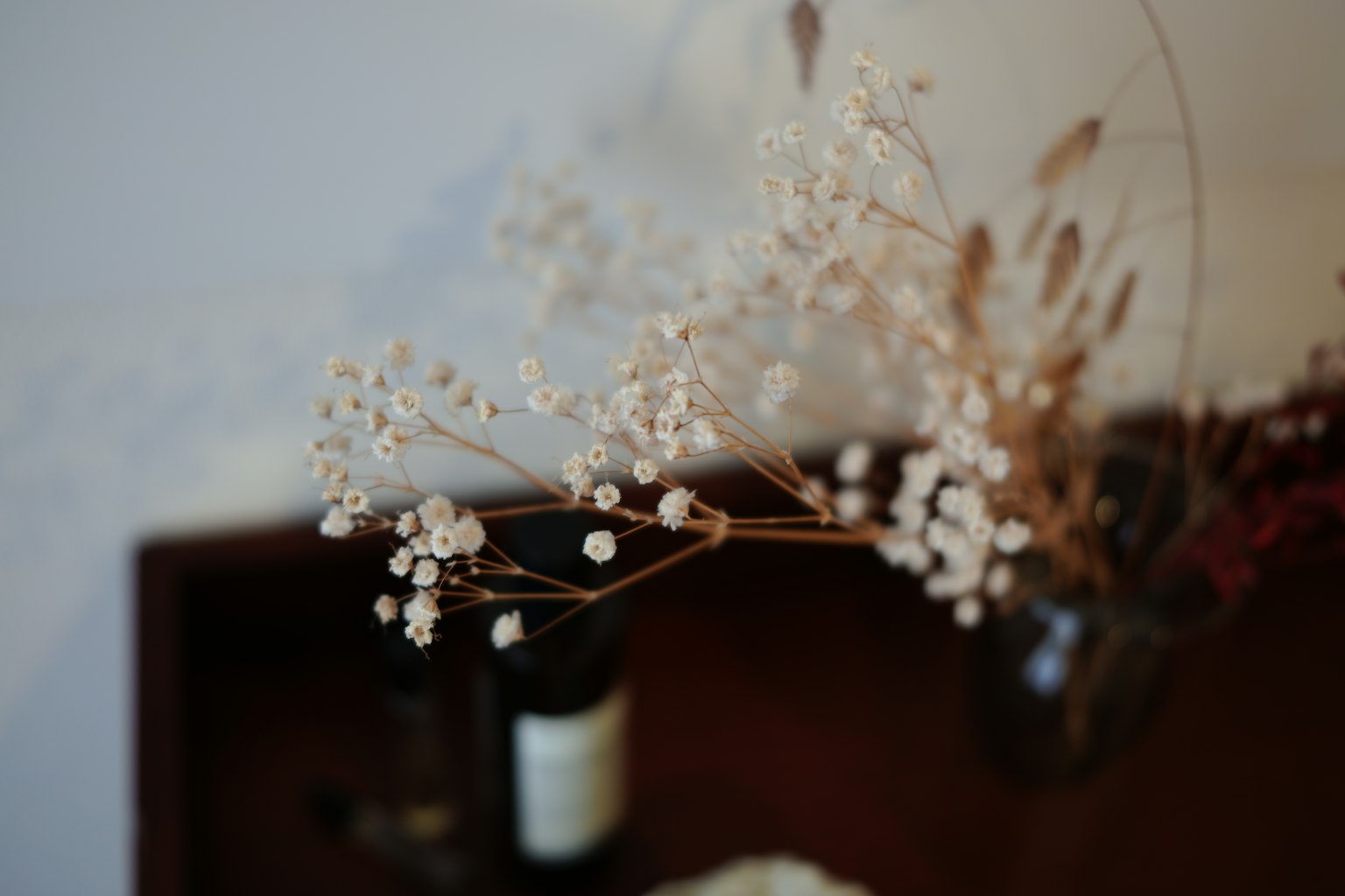 Arreglo de flores secas con una botella en una mesa de madera