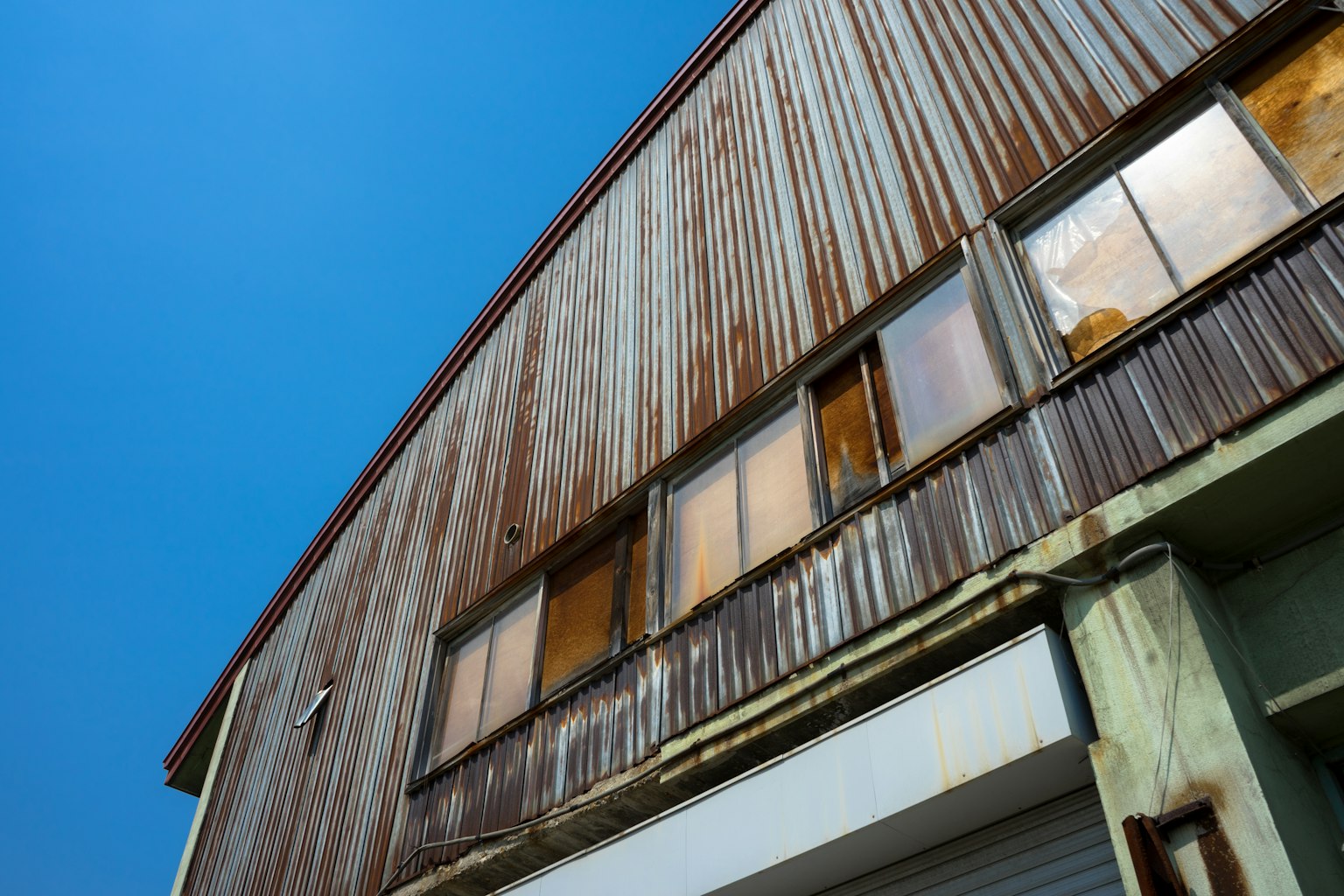 Exterior de un viejo edificio de metal contra un cielo azul Ventanas sucias y fachada oxidada son características destacadas