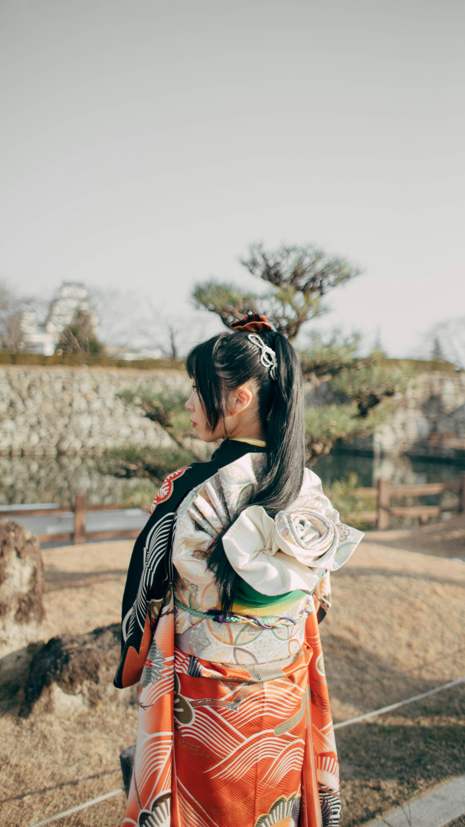 Người phụ nữ trong kimono truyền thống đứng trong vườn quay lưng lại