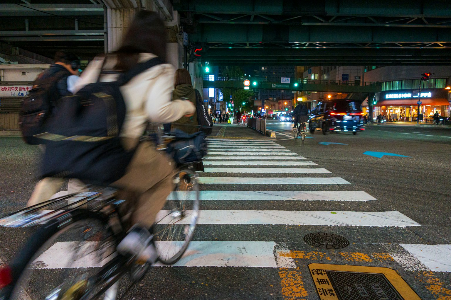 Una persona montando una bicicleta cruzando un paso de peatones de noche con luces de tráfico