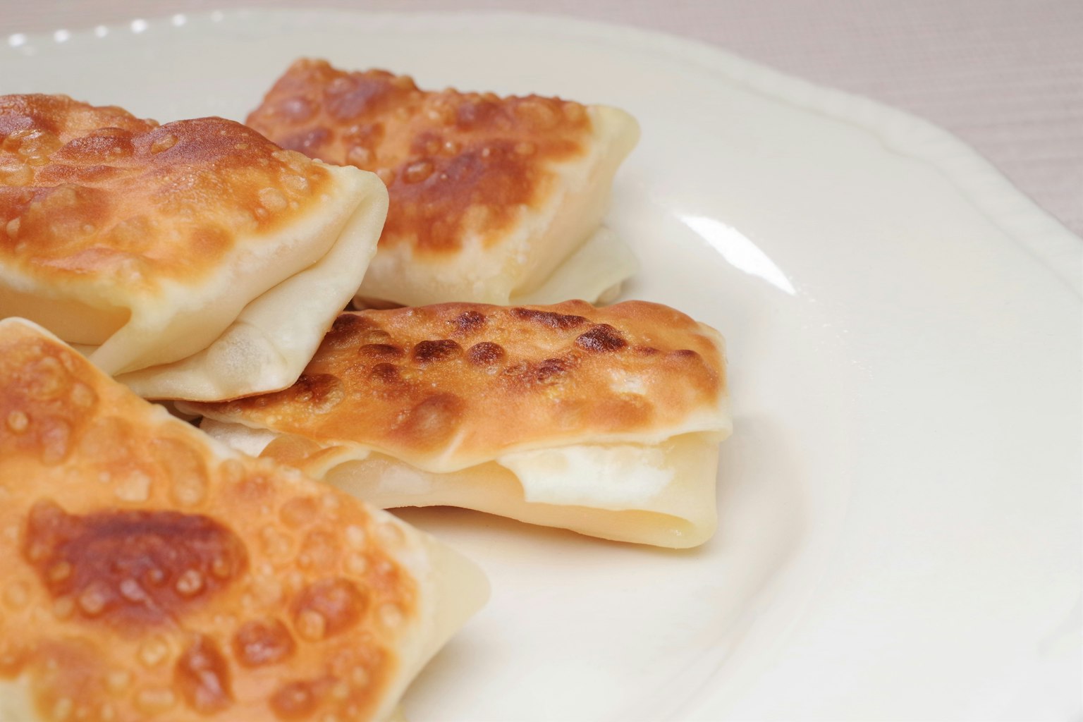 Pangsit goreng disusun di atas piring putih