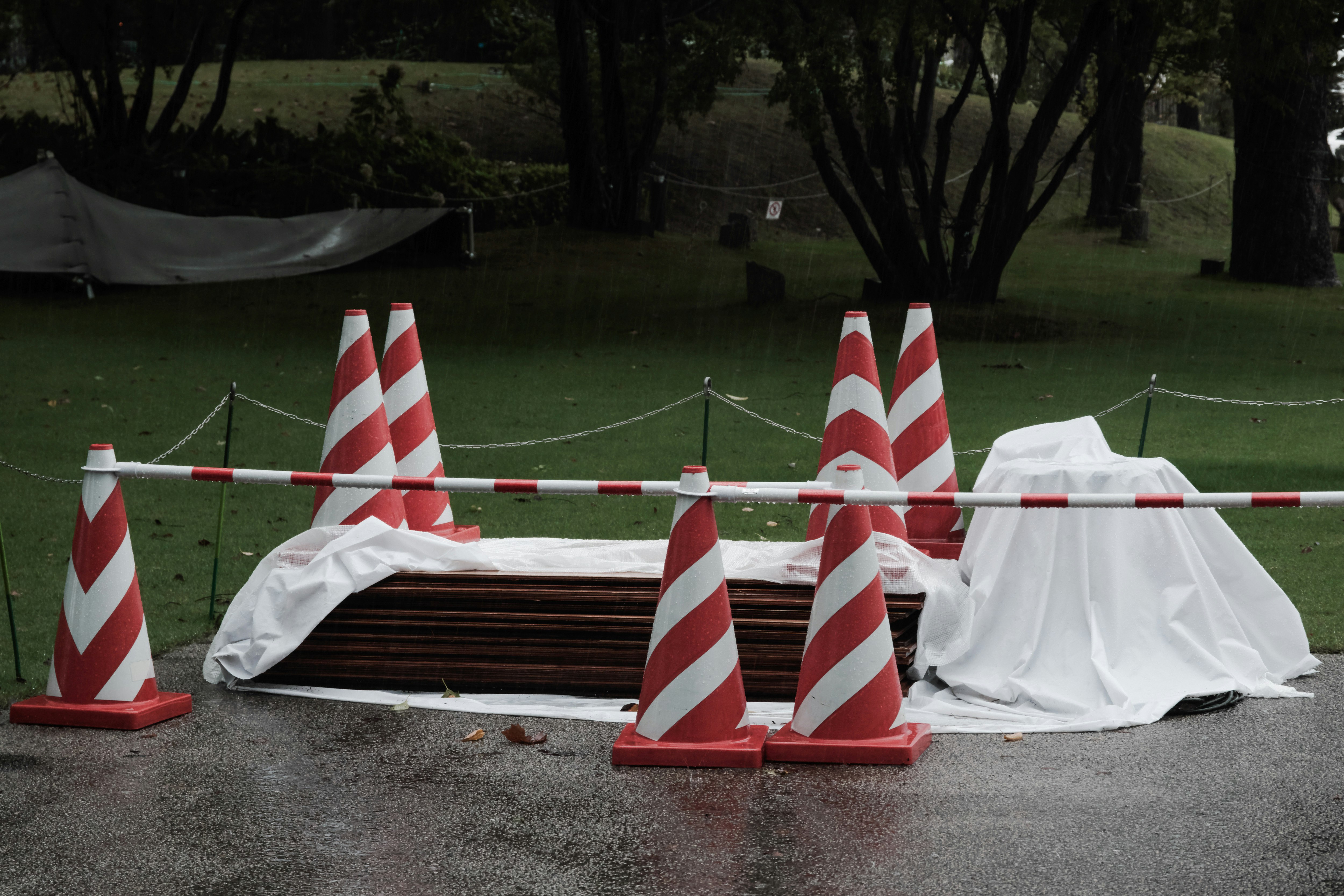 雨上がりの屋外で並ぶコーンとテントの資材保管
