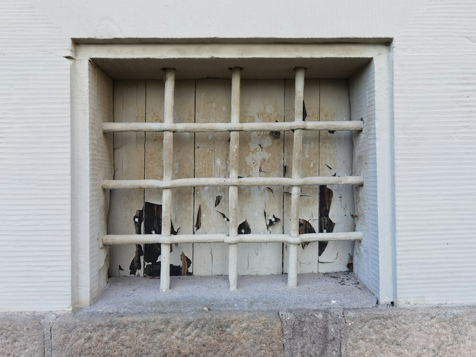 A white lattice structure mounted on a wall with partially visible black elements behind it