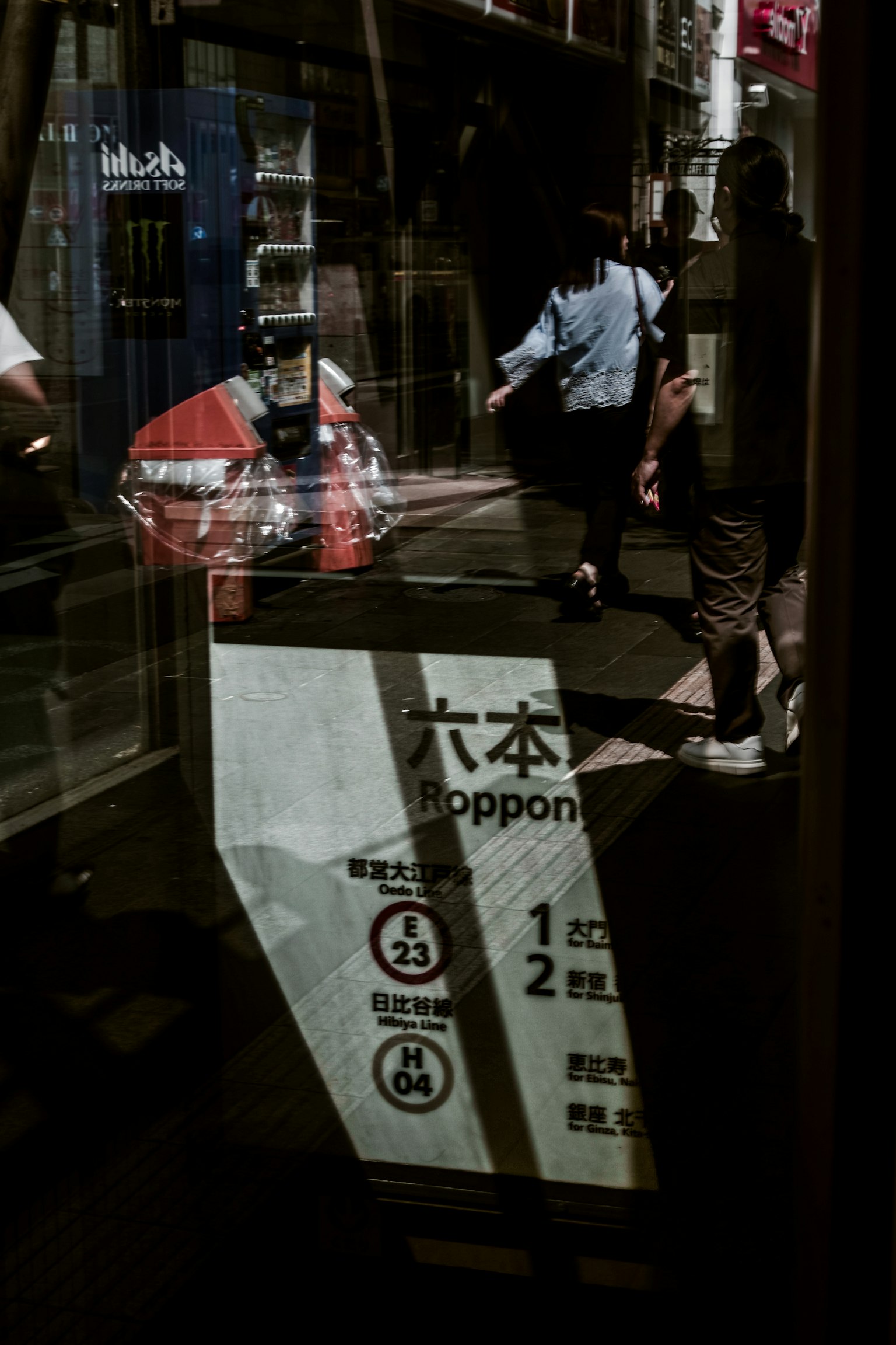 Insegna a un angolo di strada a Roppongi con riflessi di pedoni