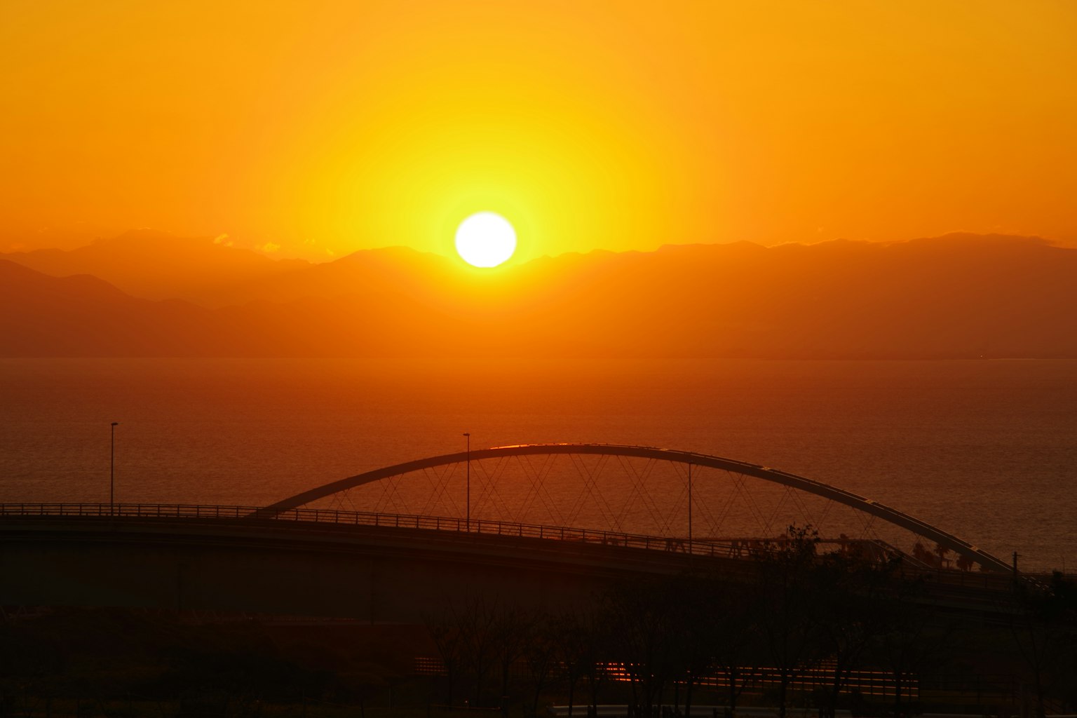 Schöner Sonnenuntergang über dem Ozean mit der Silhouette einer Brücke