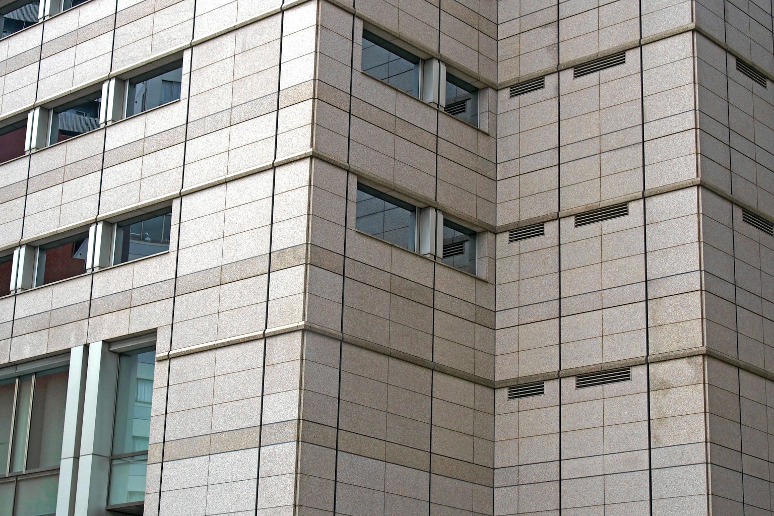 Nahaufnahme der Fassade eines modernen Gebäudes mit Fenstern und Steintextur
