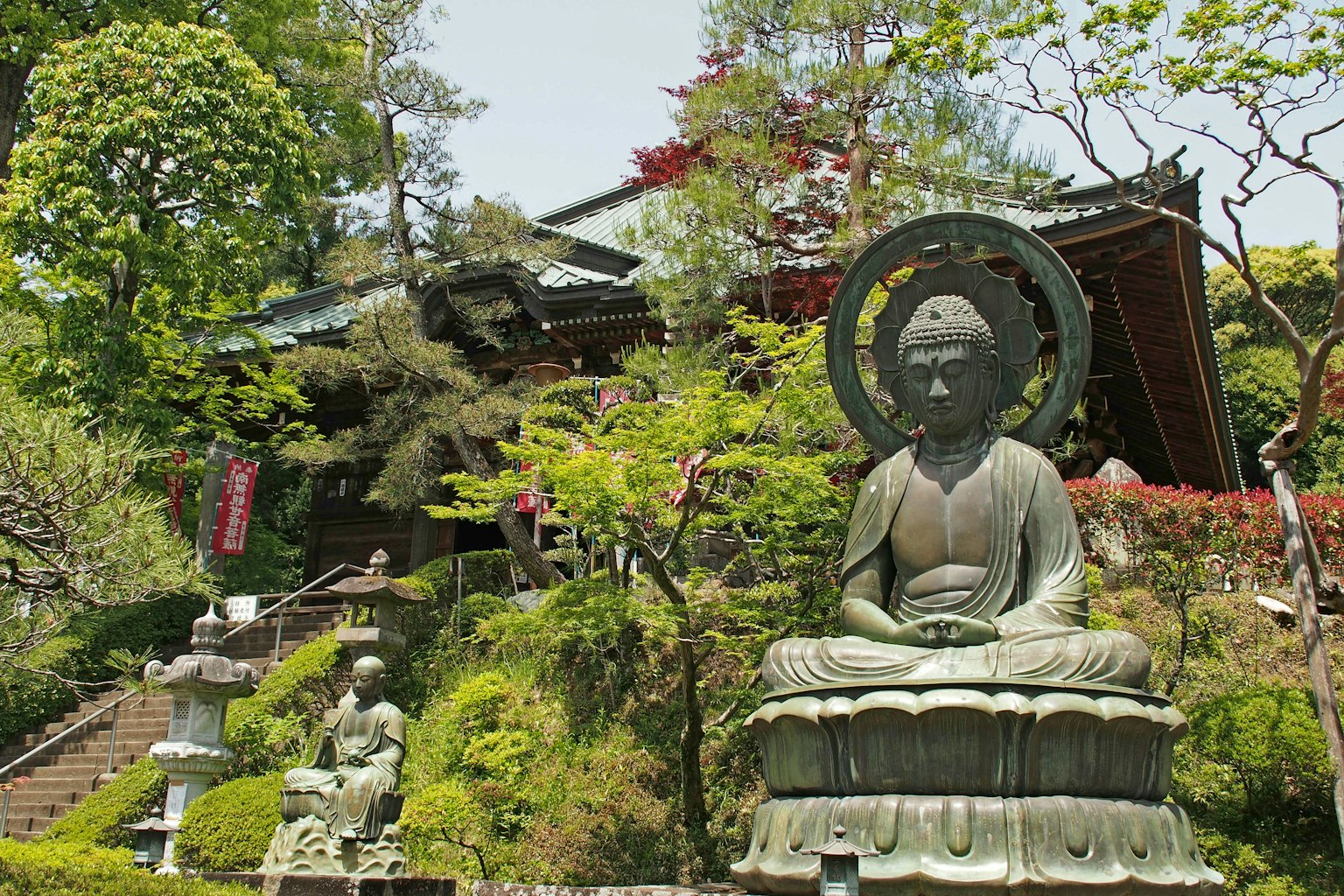 一个宁静的佛像在郁郁葱葱的花园中，背景为一座寺庙