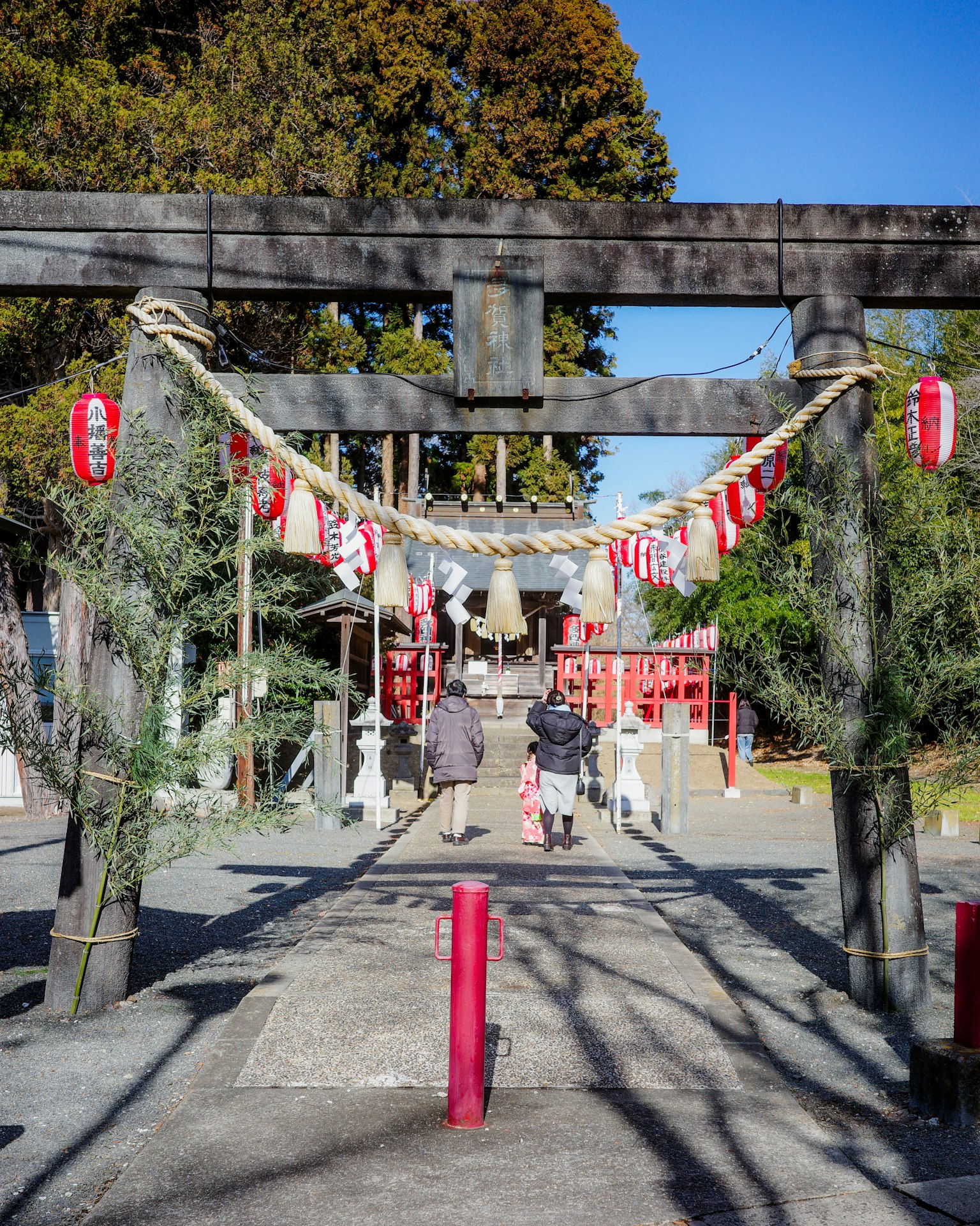 Vista di un torii di santuario con lanterne e visitatori che camminano lungo il sentiero